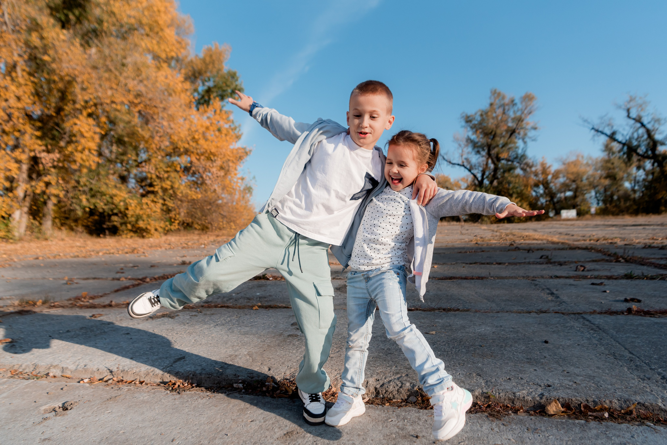 Брат и сестра балуются на фоне осенний природы рядом с Волжским