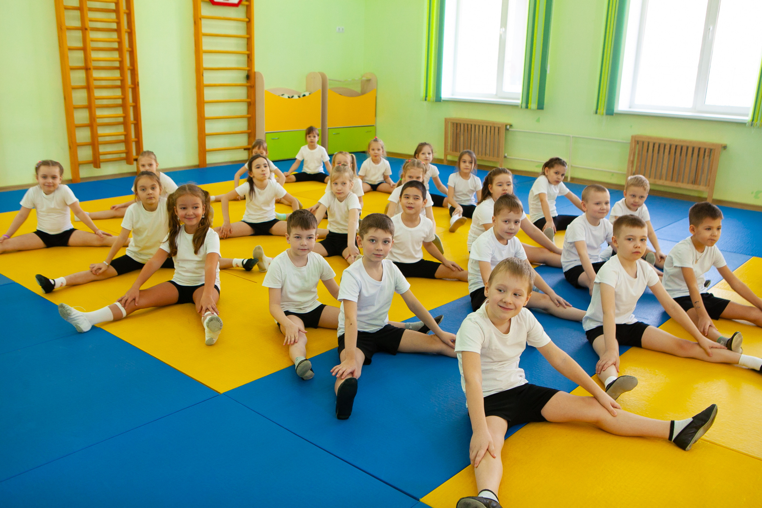 Дети в спортивном зале детского сада делают зарядку.