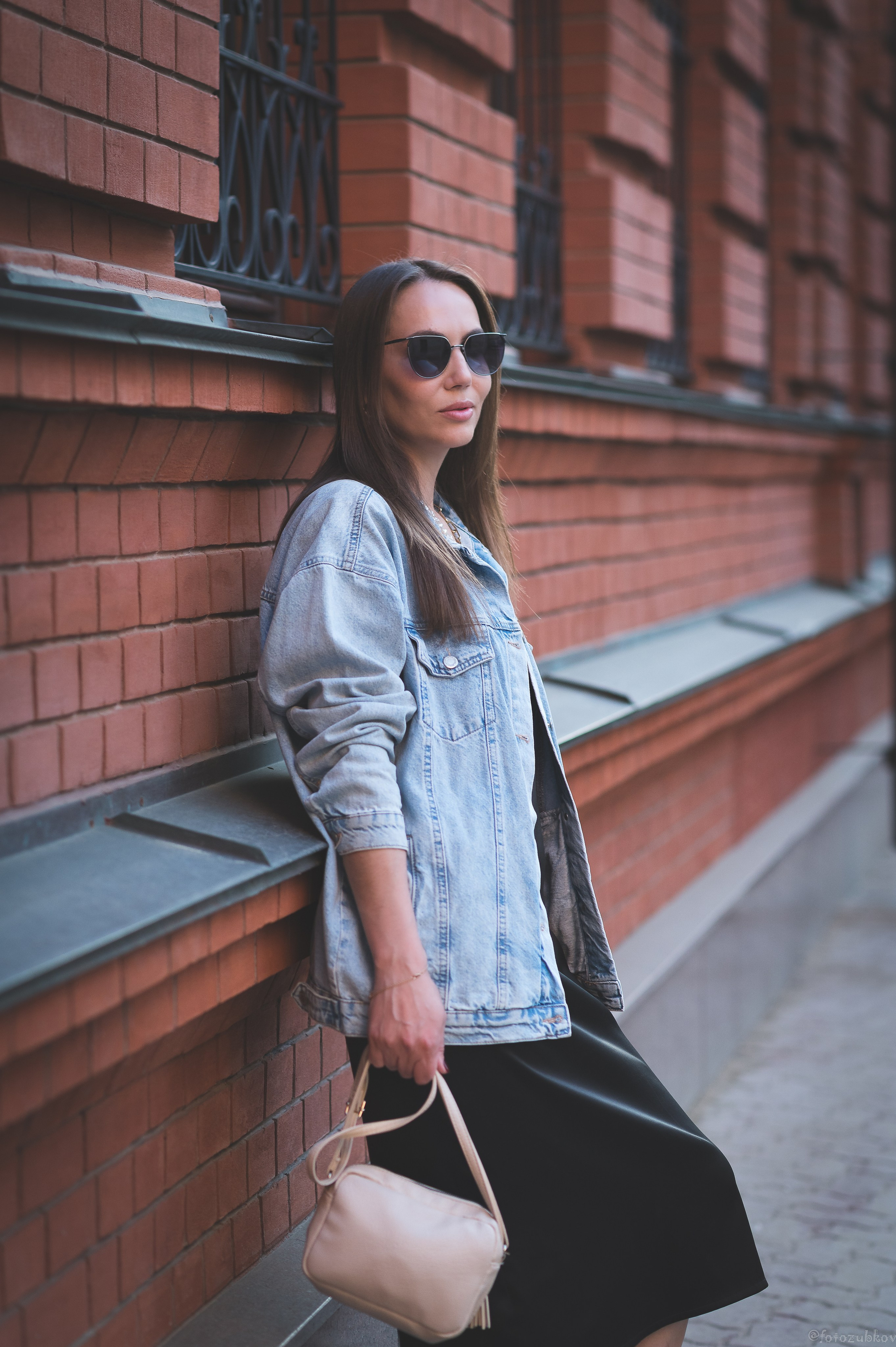 Девушка в джинсовке на фоне стены из кирпича