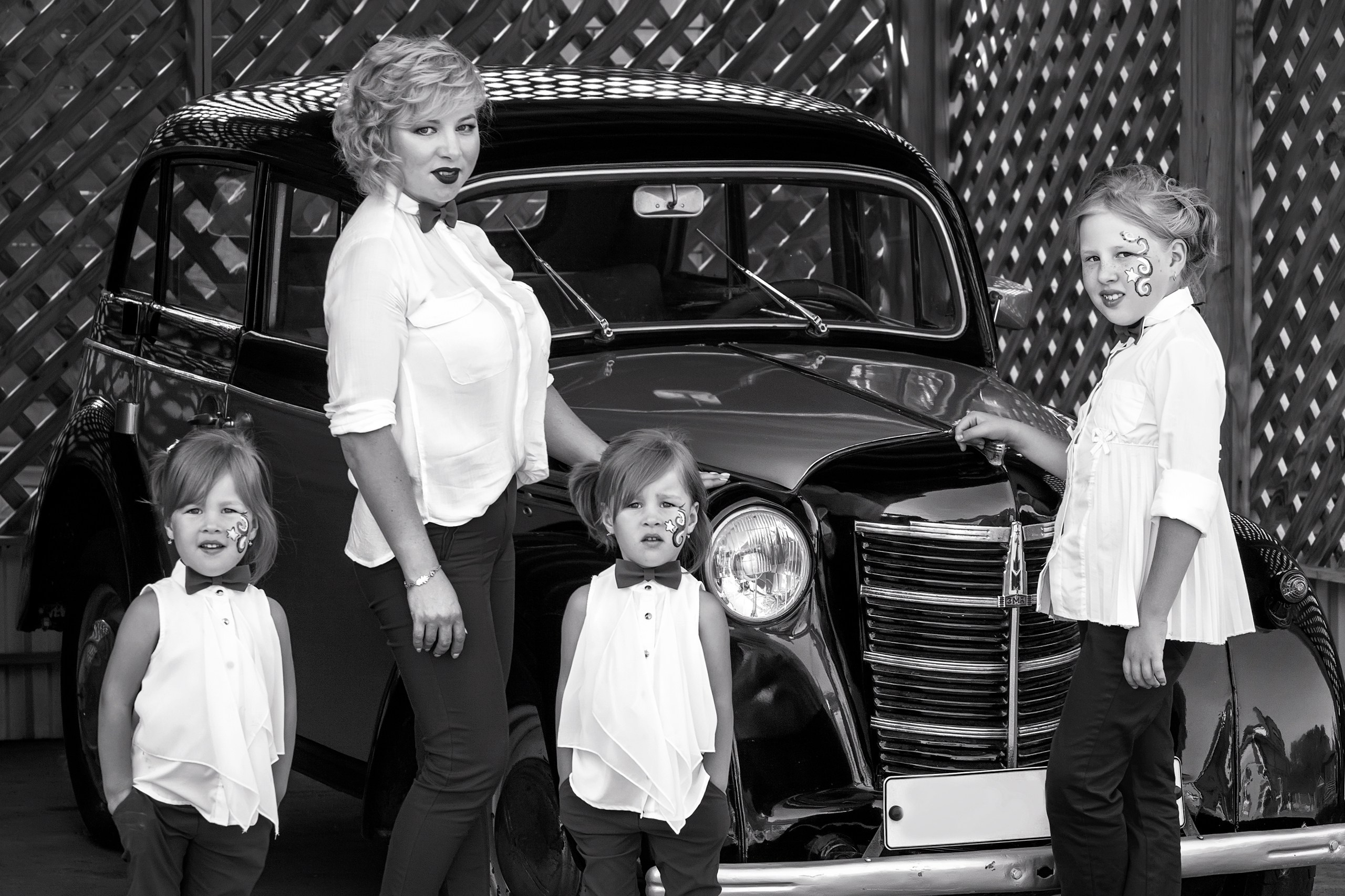 Семейный черно-белый портрет мамы с дочками у ретро-машины