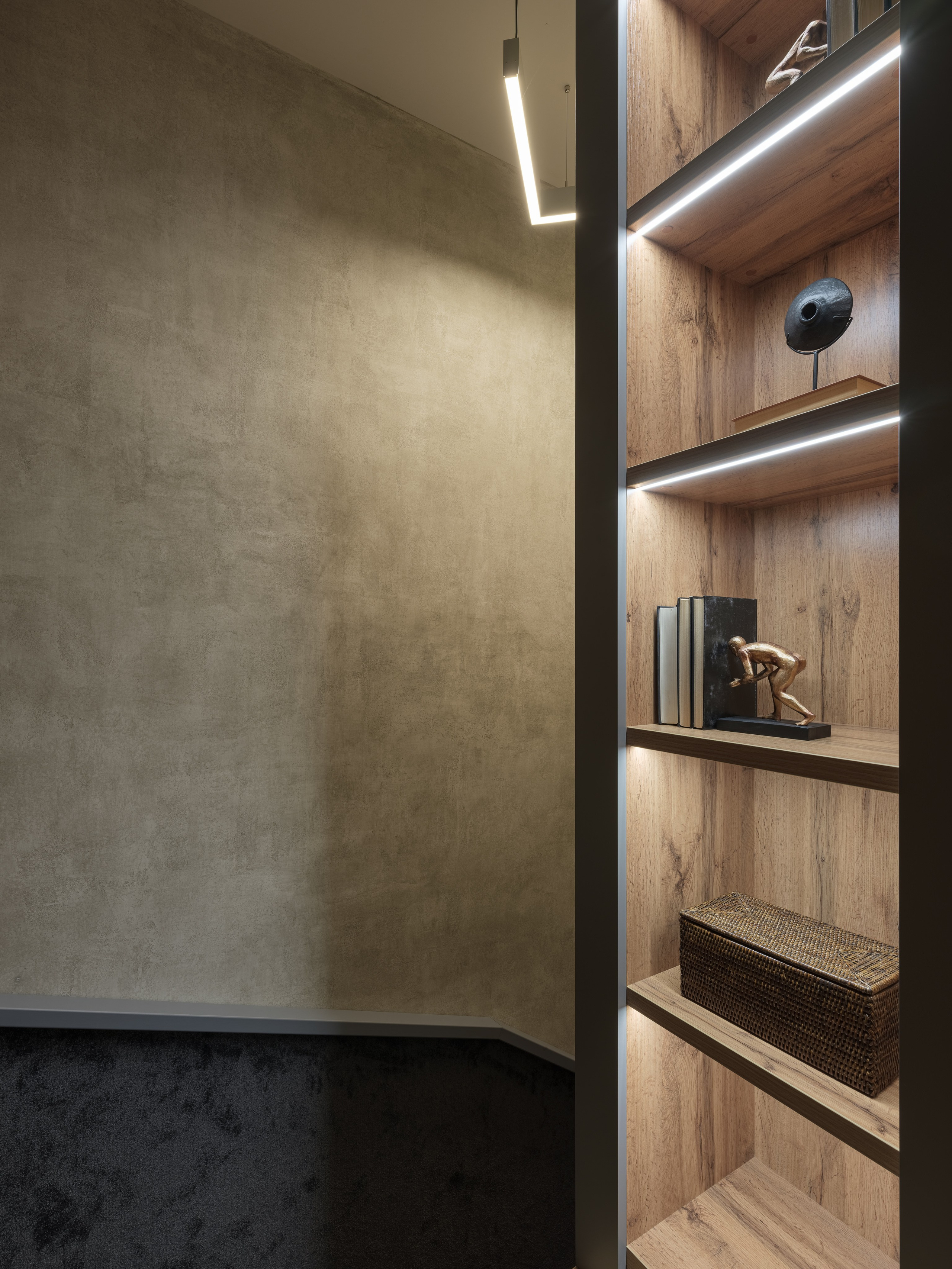 Современный интерьер холла с бетонными стенами, встроенными деревянными нишами и подсветкой, создающий атмосферу уюта и минимализма. Дизайнер Алина Дёрова, стилист Наталья Якушева, фотограф Сергей Денисенко, съёмка лестничной зоны квартиры.