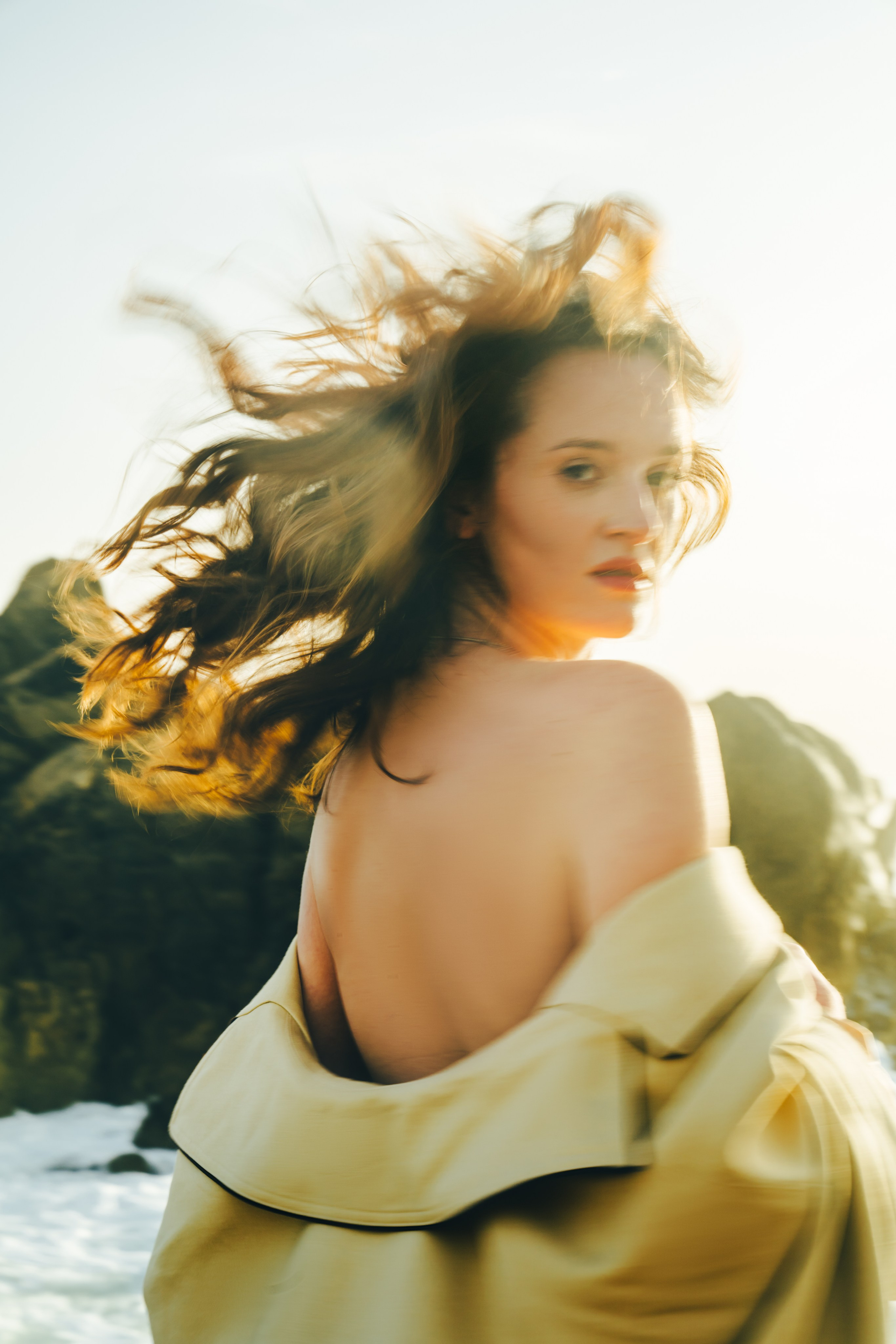 Девушка с развивающимися волосами бежит по скалистому берегу