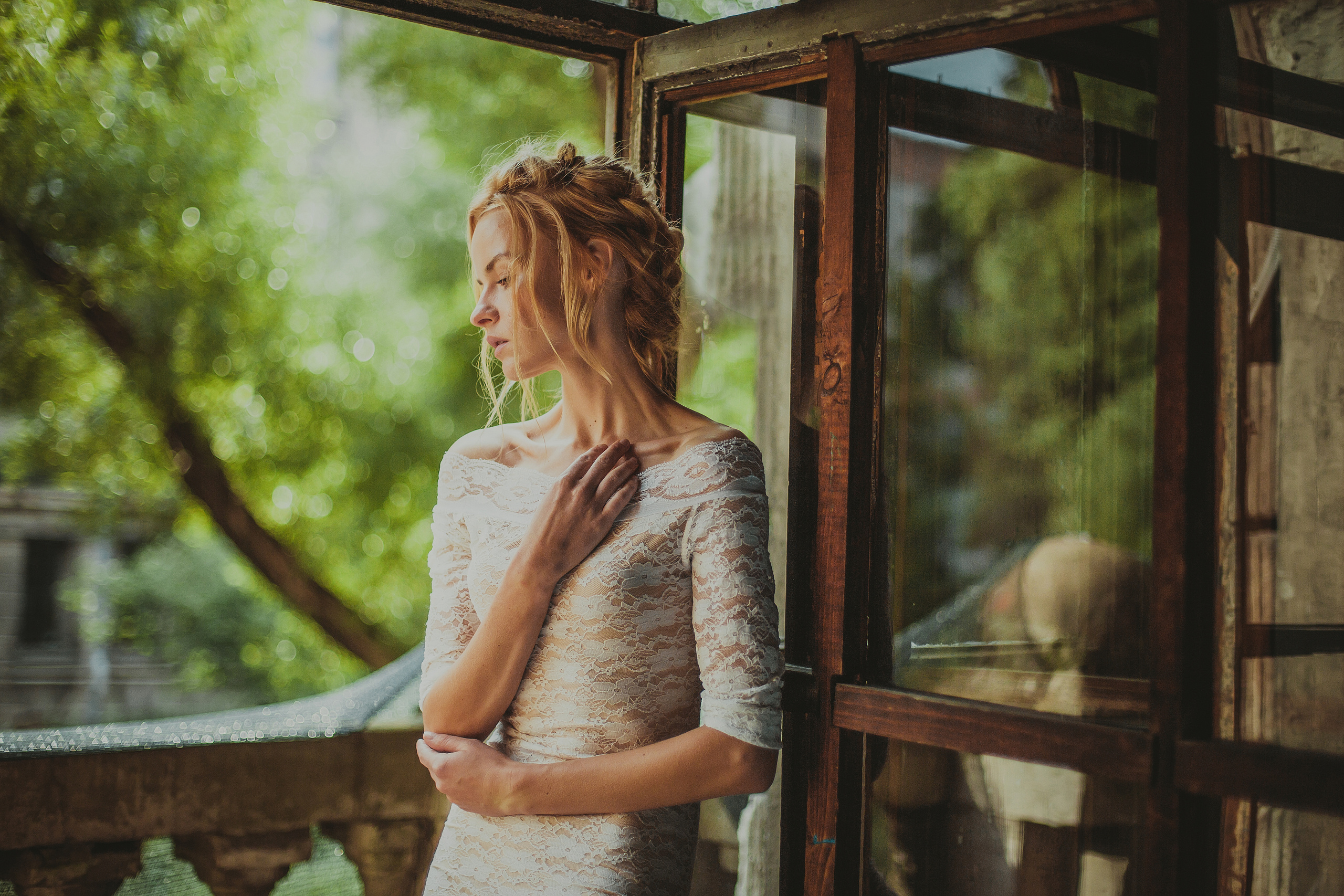 портрет блондинки в белом платье у окна с деревянной рамой