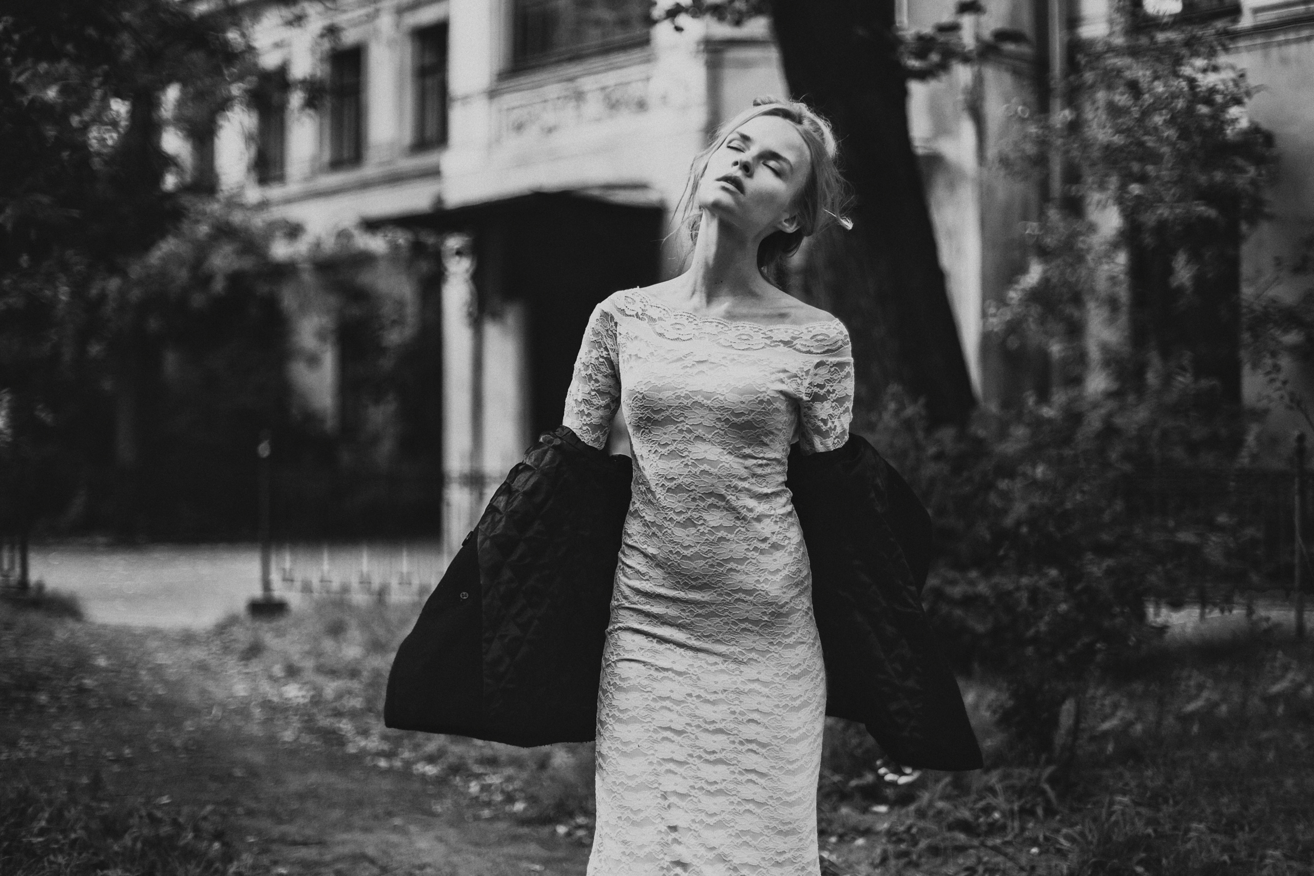 девушка в открытой куртке и белом платье подняла лицо к солнцу