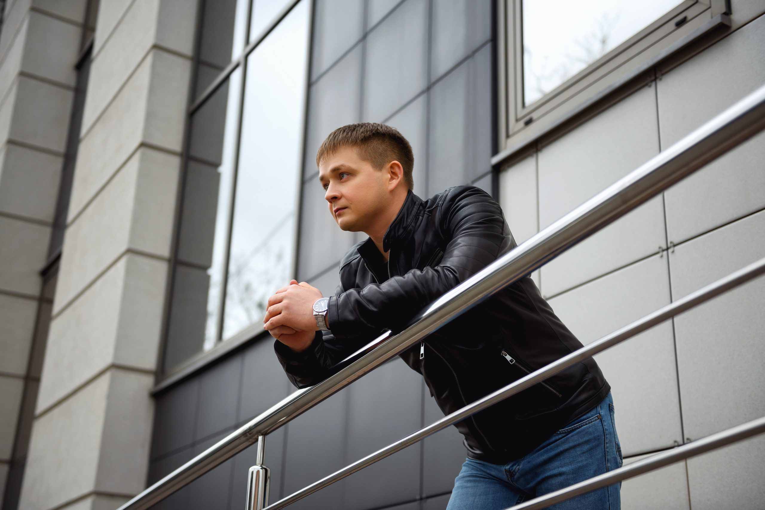 Фотосессия мужчина стоит, опираясь на перила на фоне здания