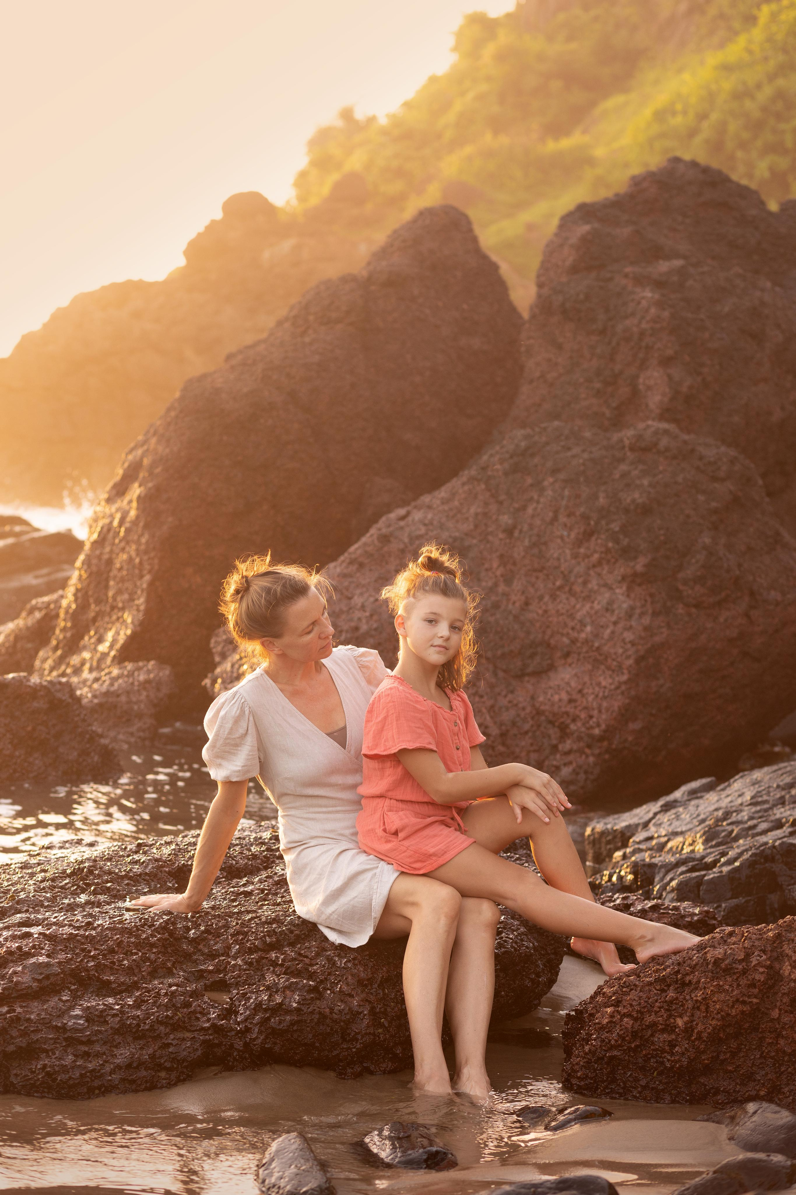 mother and daughter sitting on the rocks on the sea