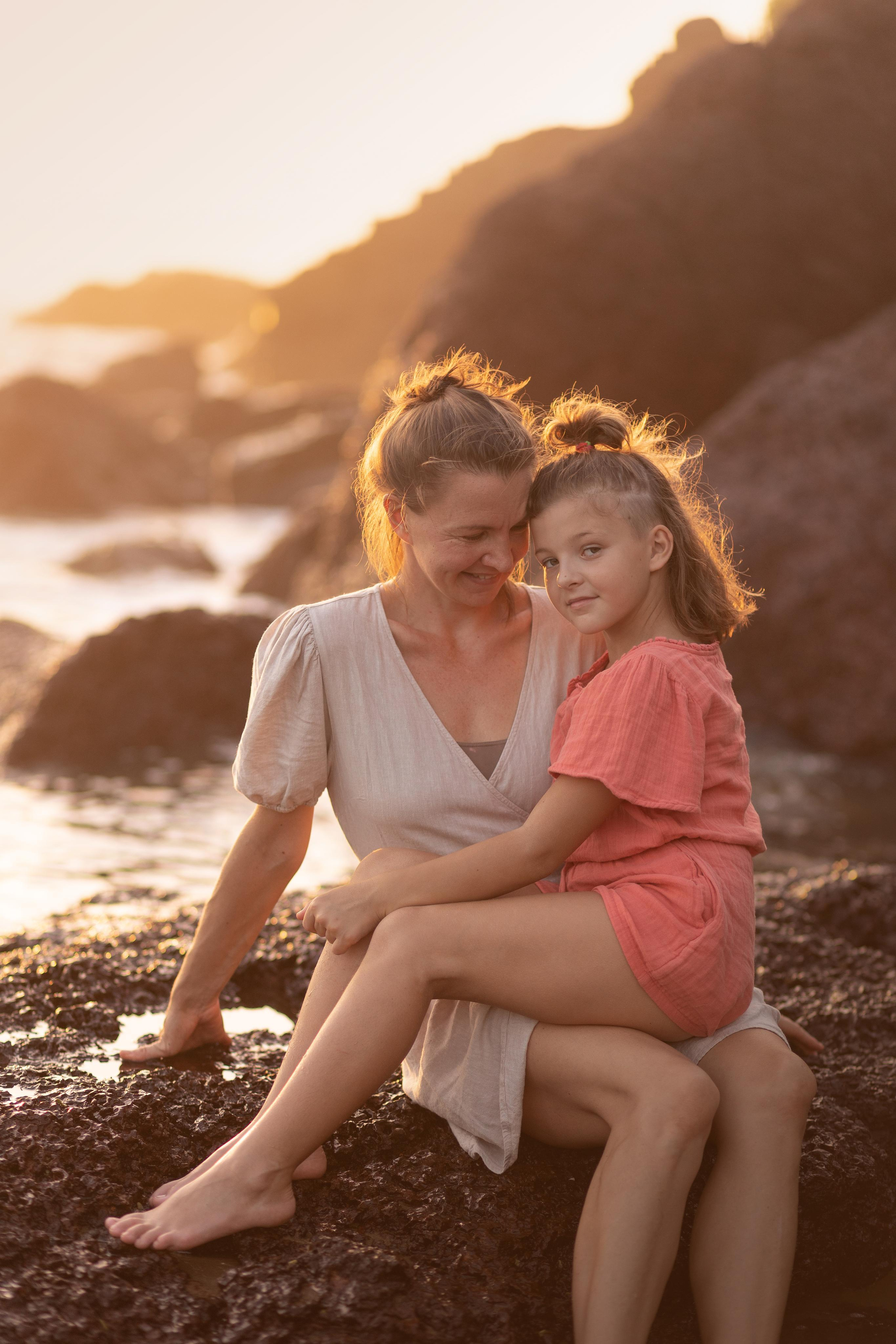 mom and daughter sitting on the rocks
