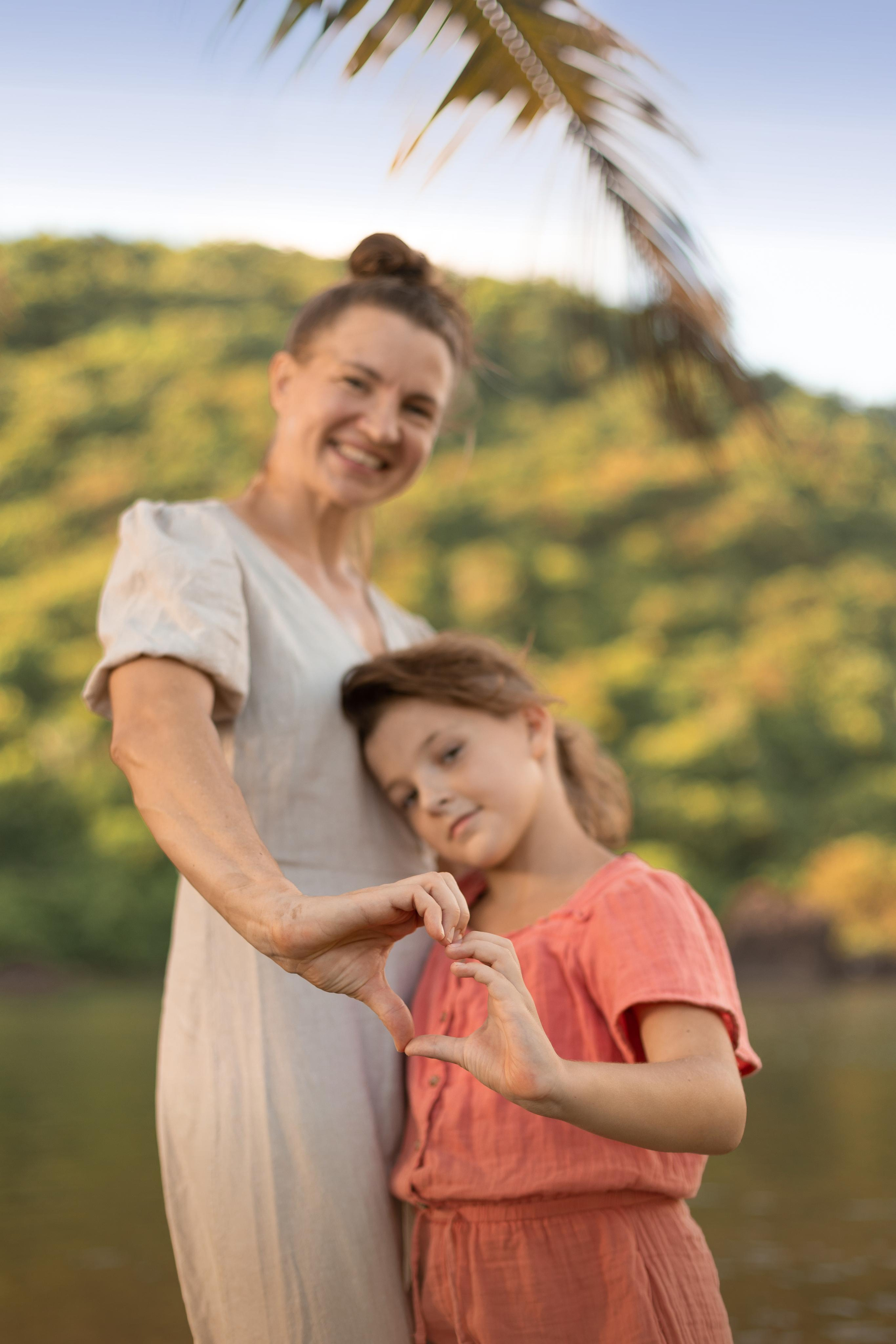 mother and daughter holding their hands in the shape of heart