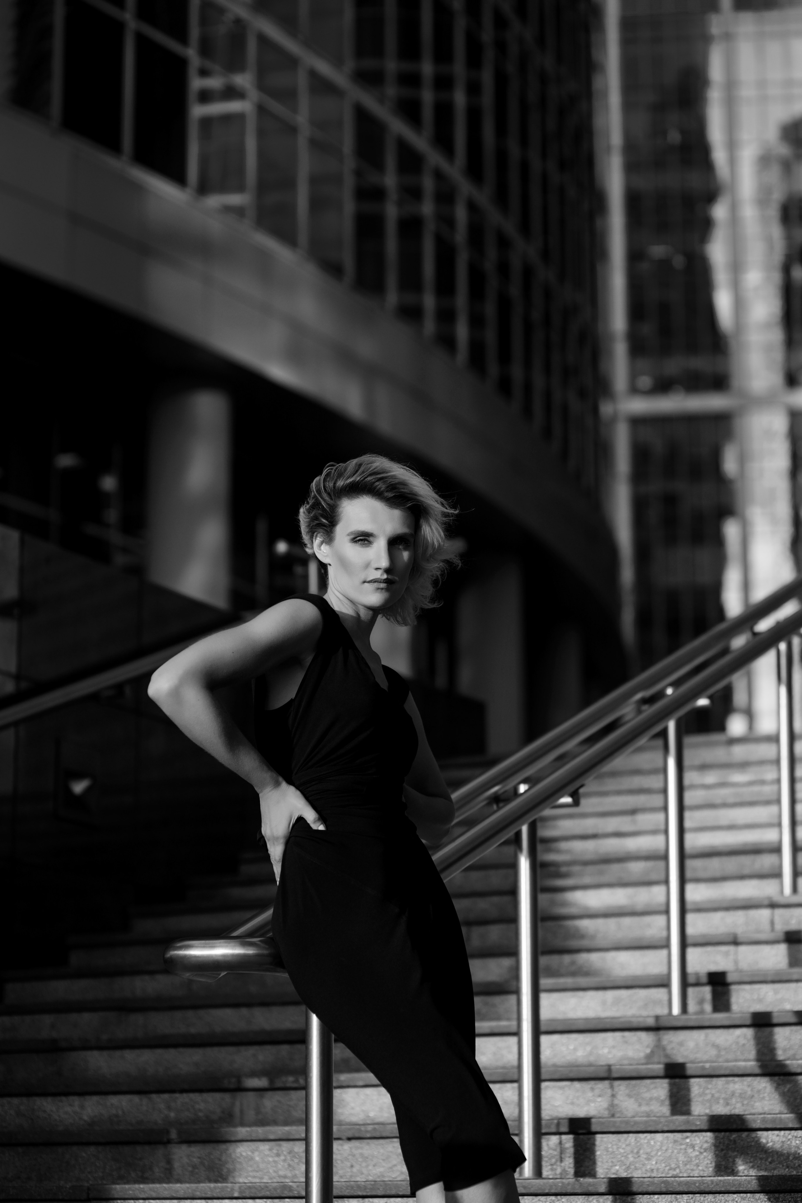 девушка в черном платье стоит на лестнице на ветру