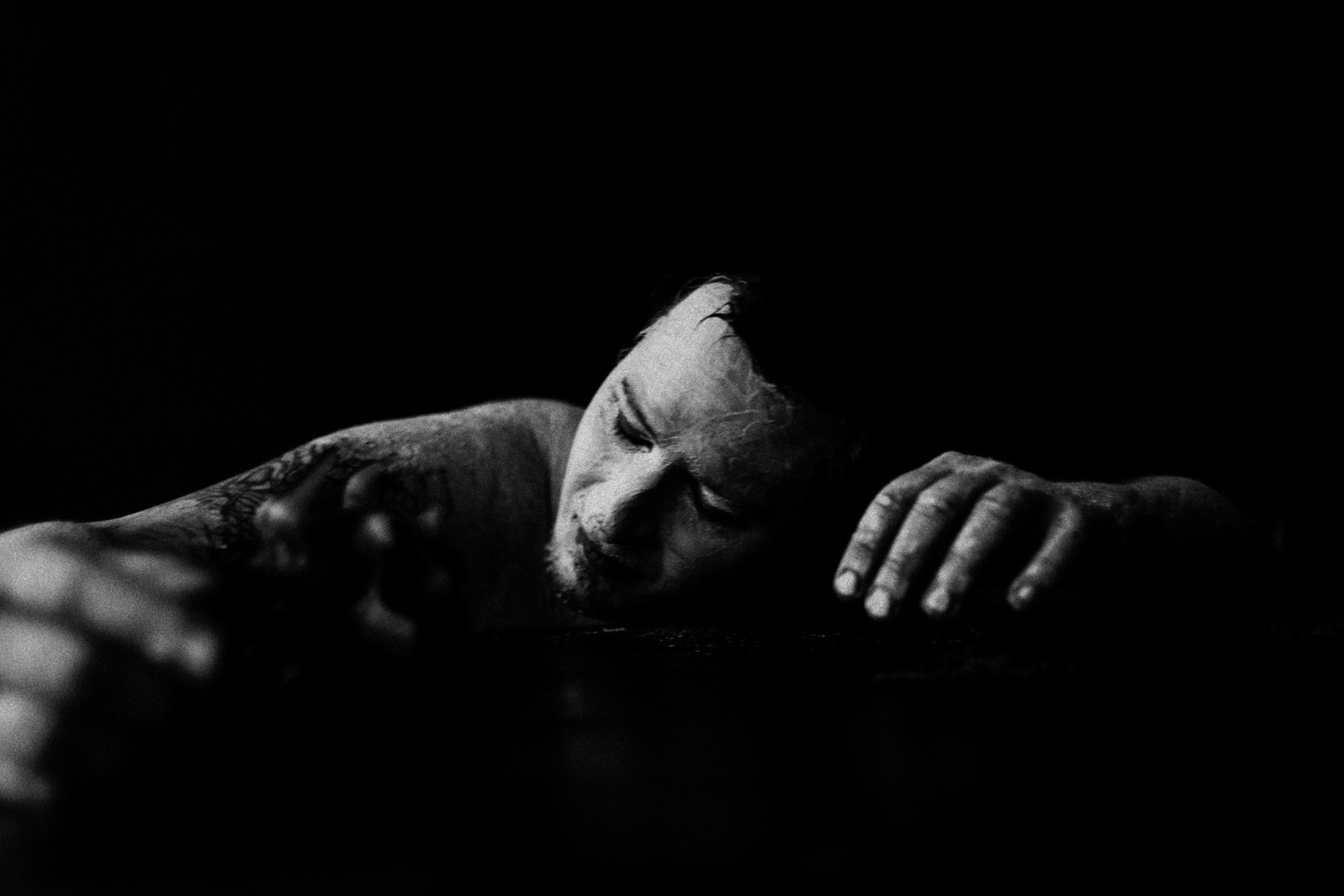 Крупный план мужского лица с художественным гримом, акцент на глазах и текстуре кожи, арт-фотография в черном ключе