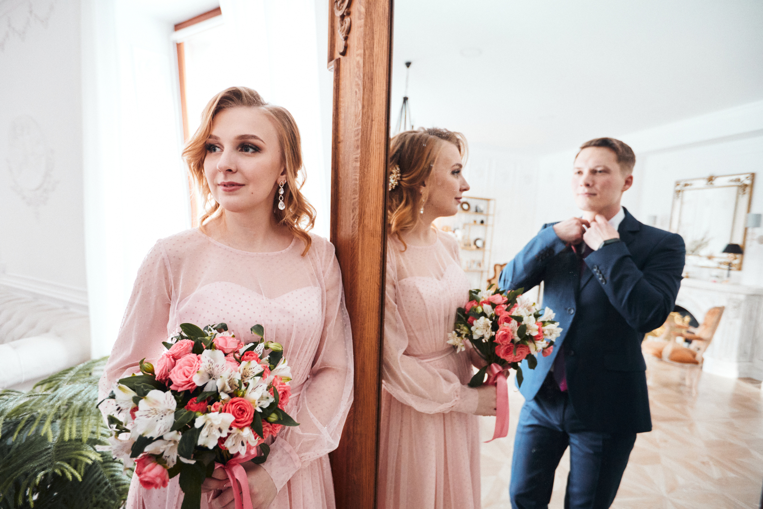 Жених и невеста на свадьбе позируют у зеркала в интерьерной фотостудии