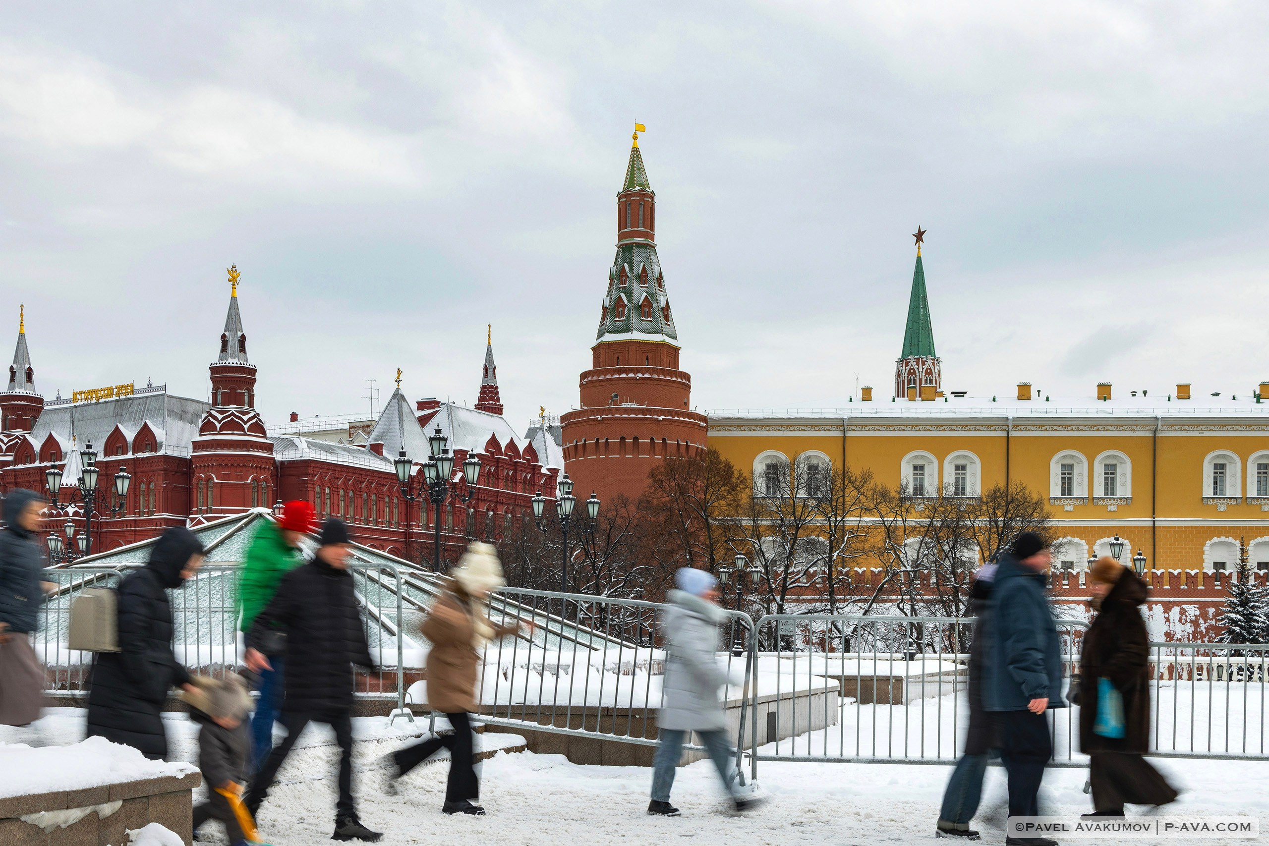 Москвичи во время прогулки на фоне забора и башен Кремля 