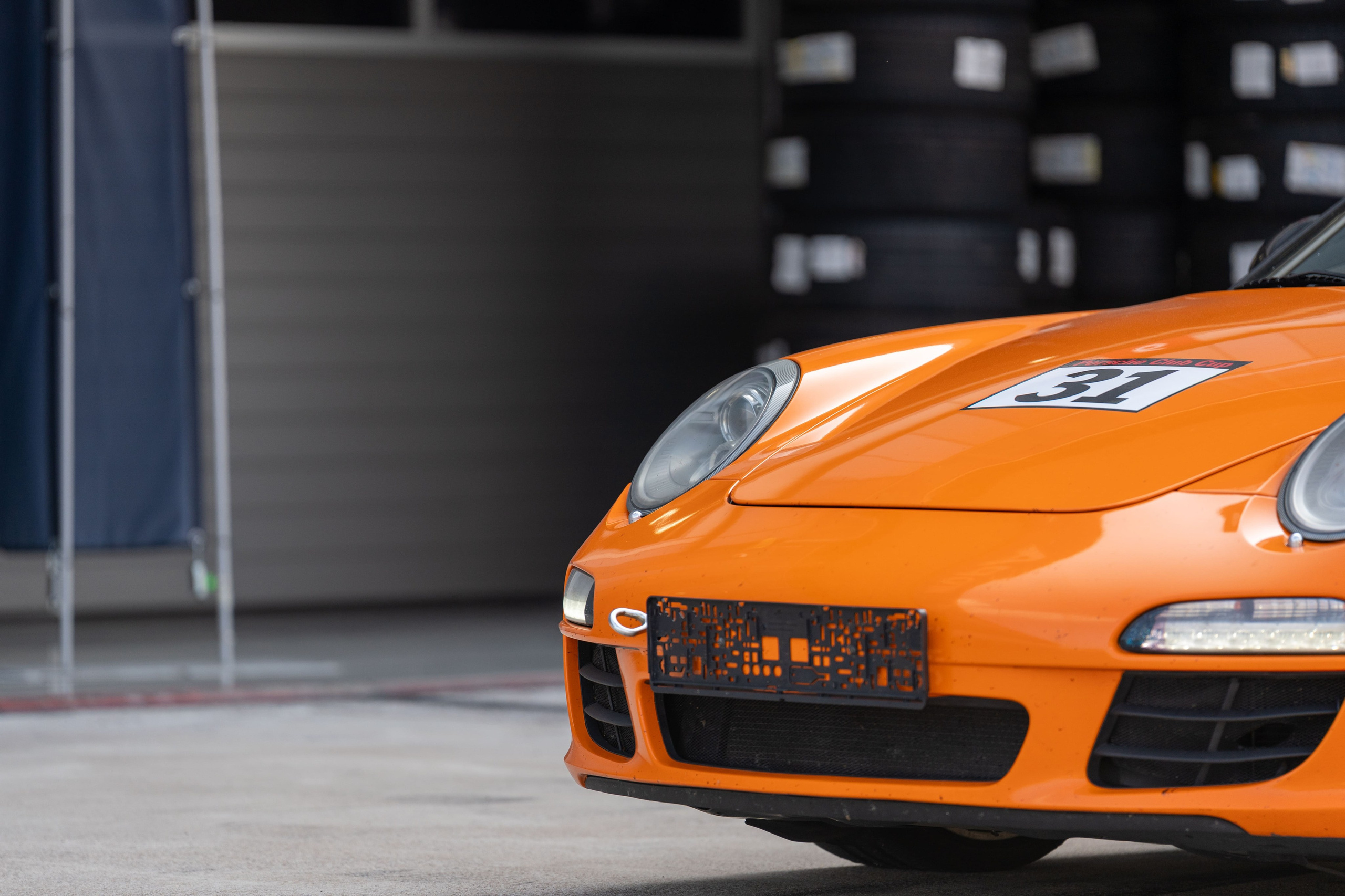 Оранжевый гоночный Porsche №31 на пит-лейне автодрома «Игора Драйв»