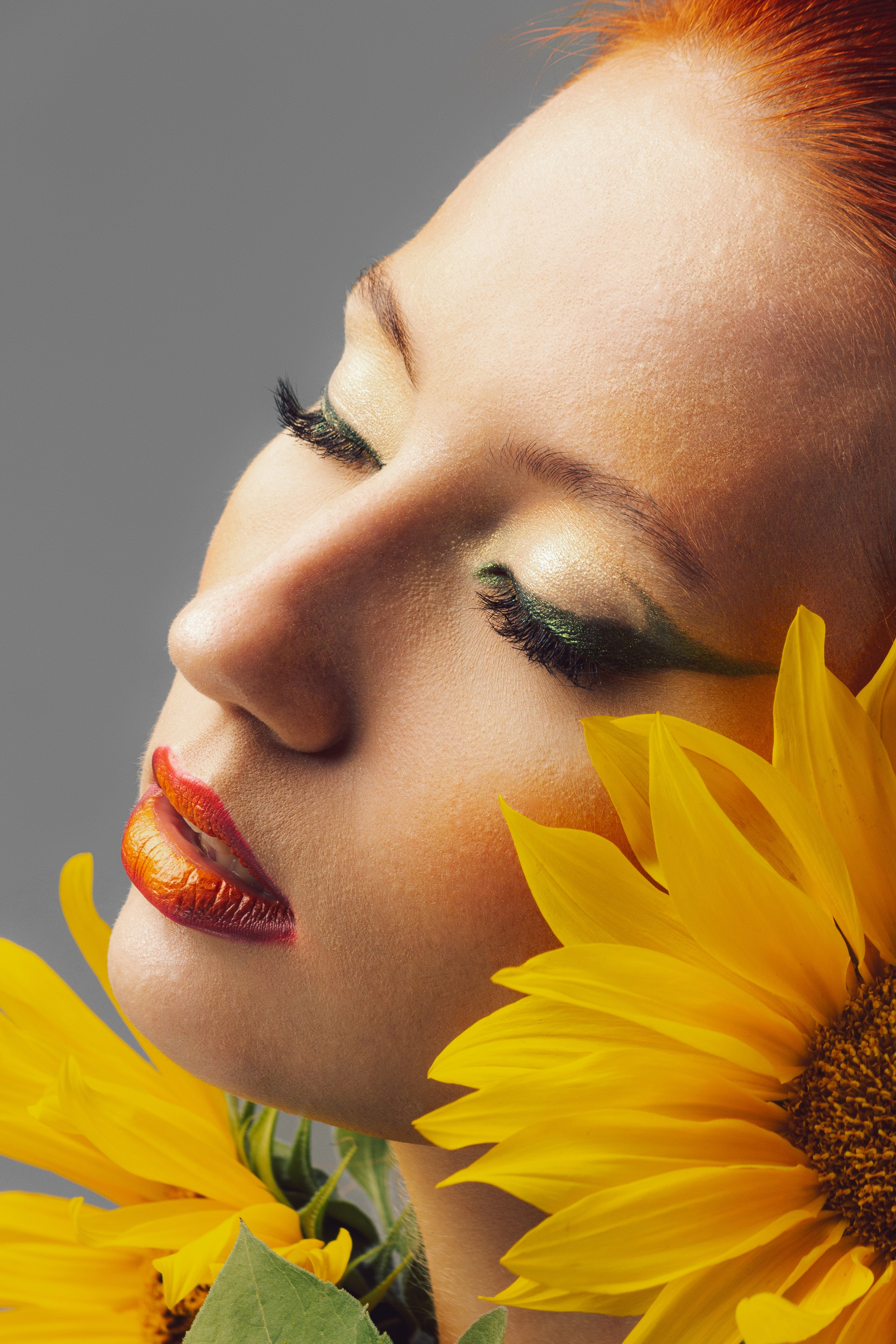 крупный портрет девушки с закрытыми глазами среди подсолнухов 