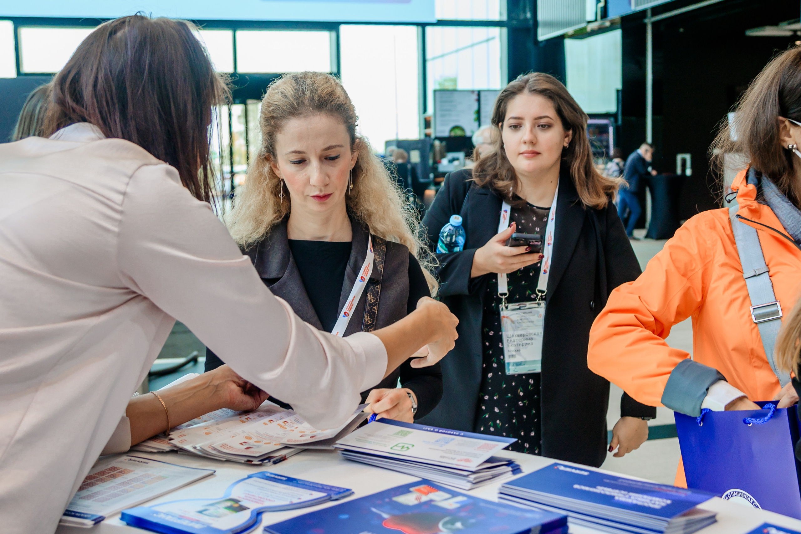 Женщина работающая на рекламном стенде на выставке собирает информационные материалы для гостей