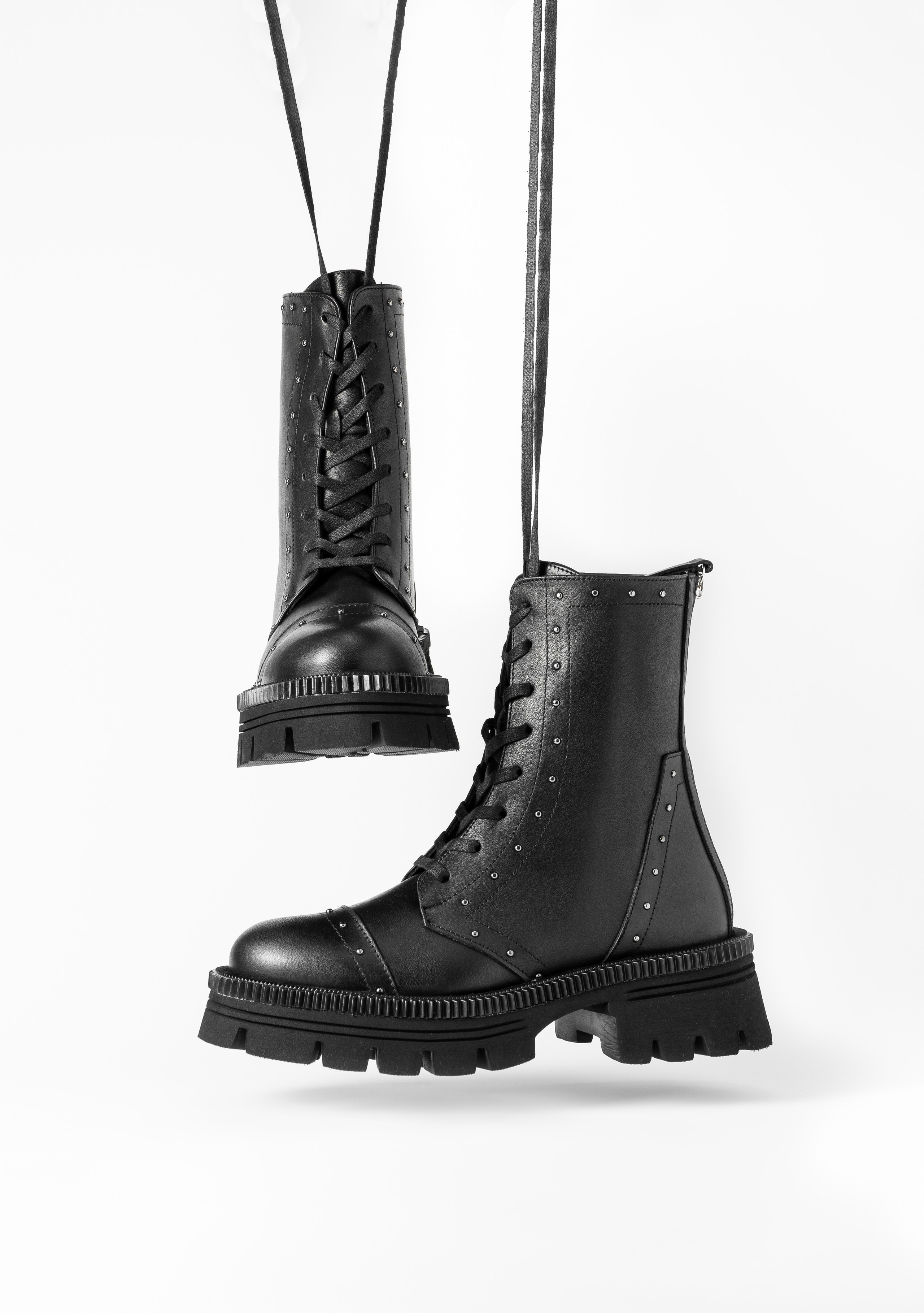 Пара модных трендовых ботинок на белом фоне с падающей тенью.