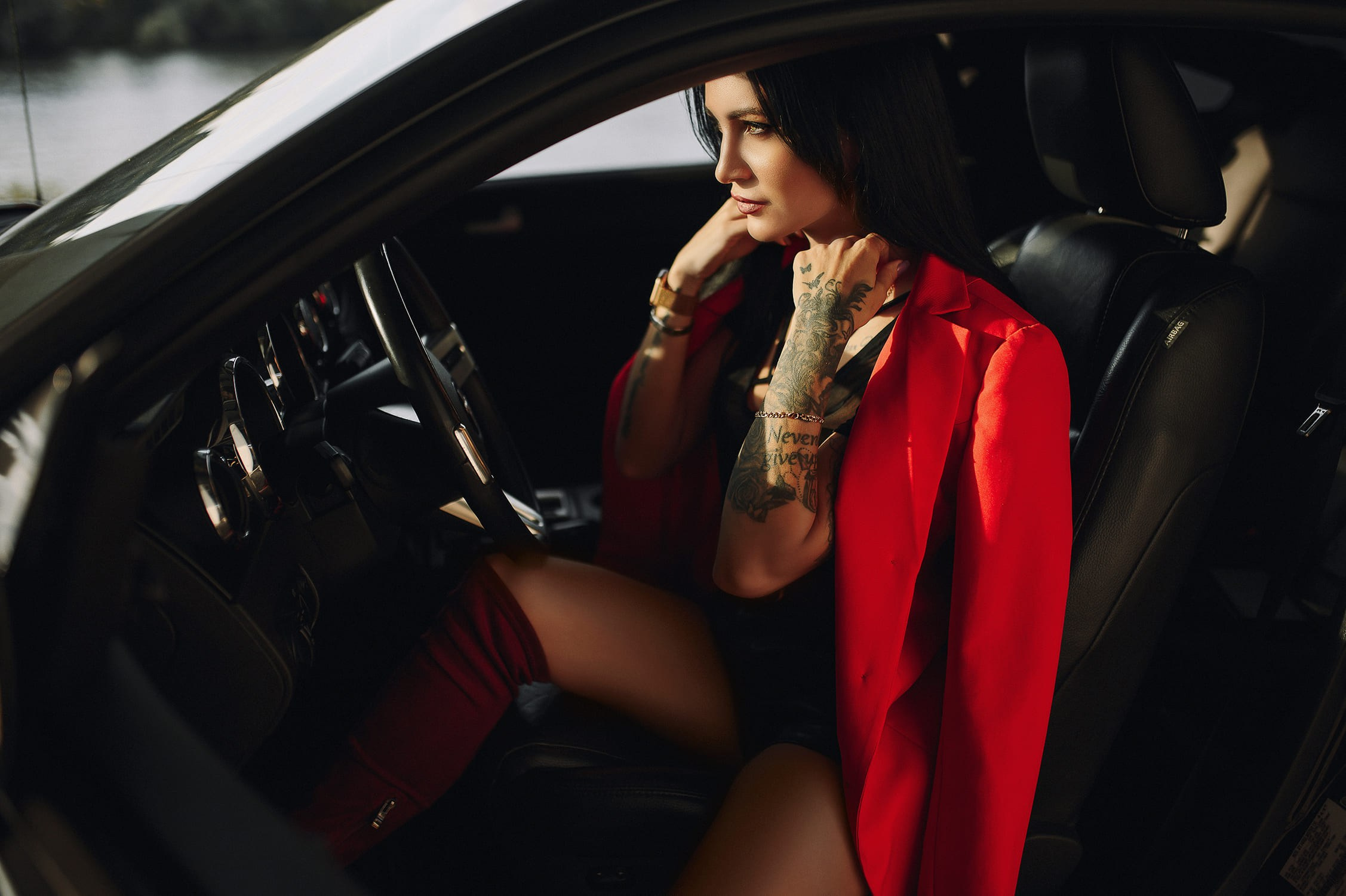 Модель в красном пиджаке сидит в машине