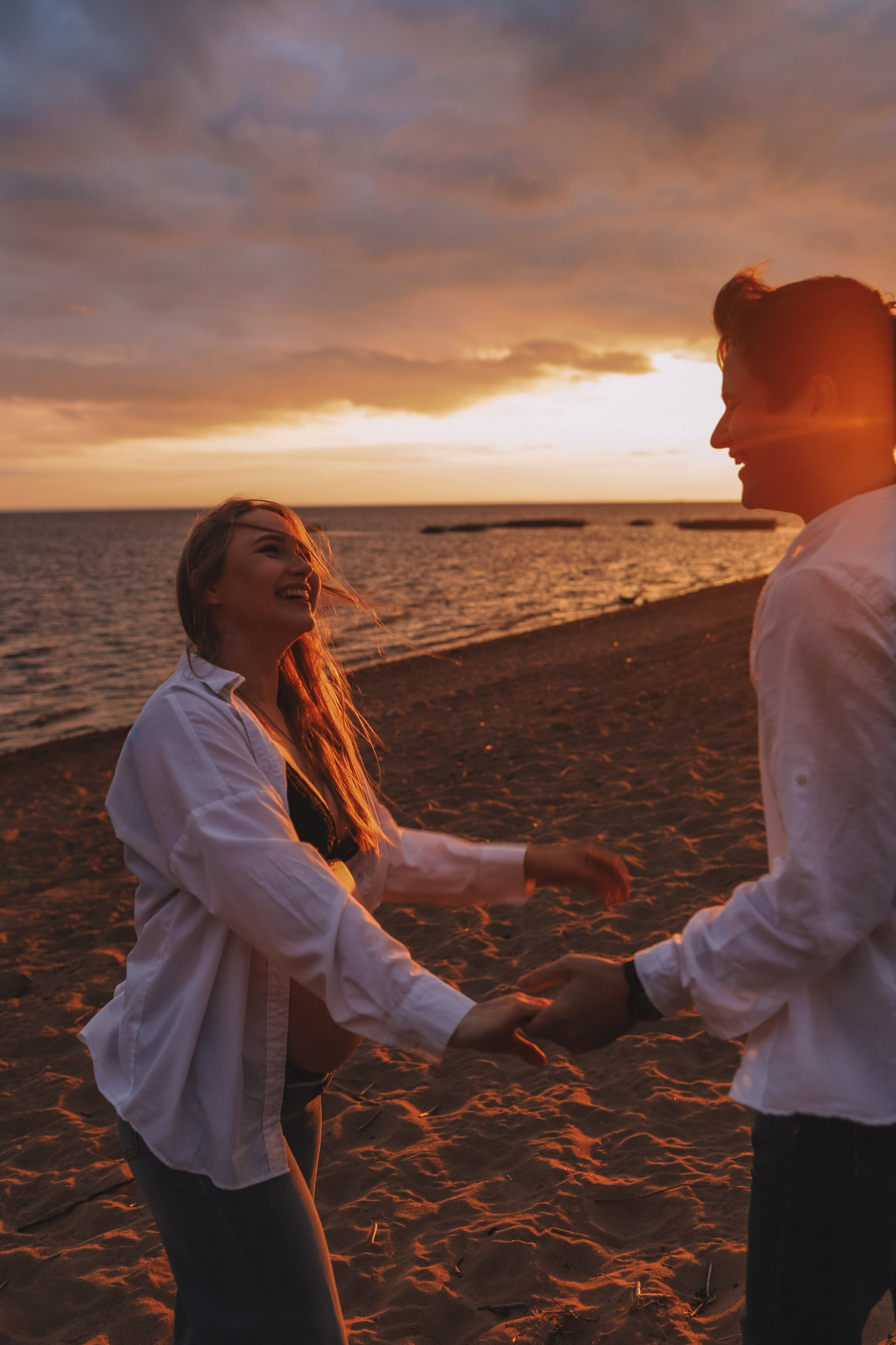 Пара идёт вдоль берега, закат, силуэты