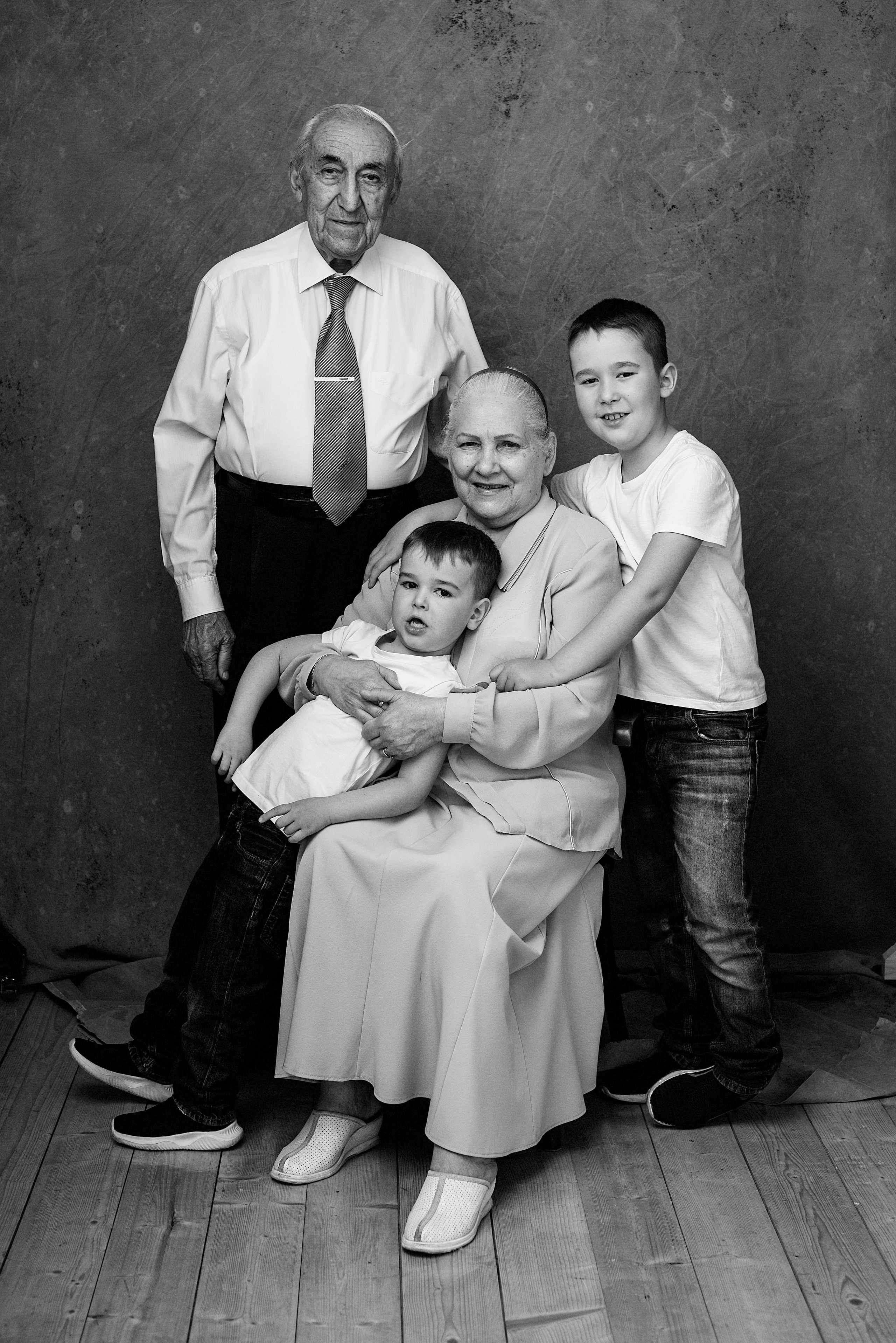 Бабушка и дедушка сидя обнимают внуков