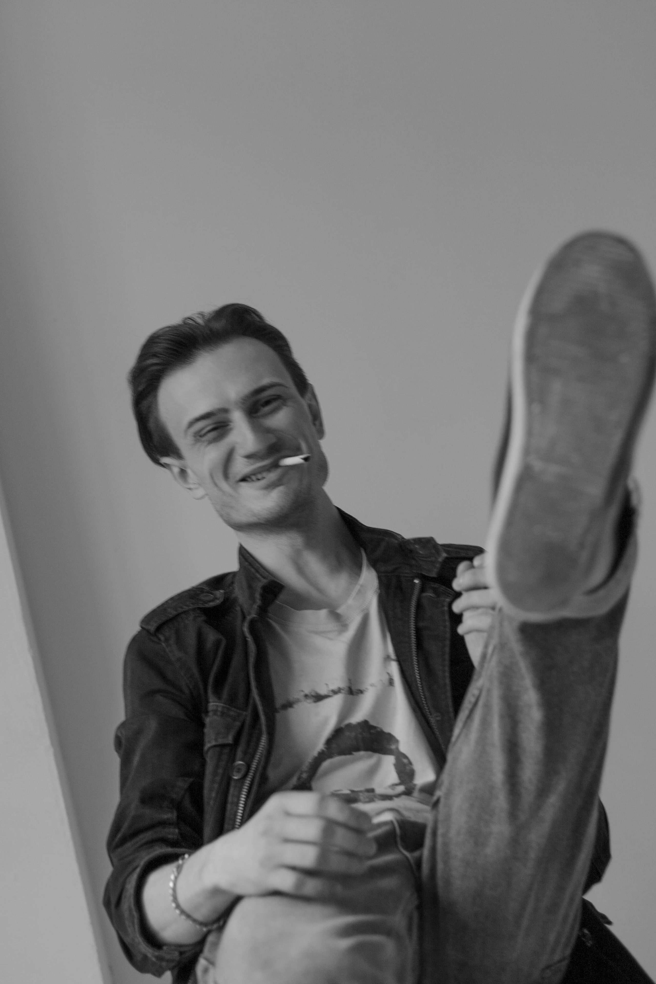 Мужчина вытянул ногу в кедах вперёд. Мужчина с сигаретой смеётся.