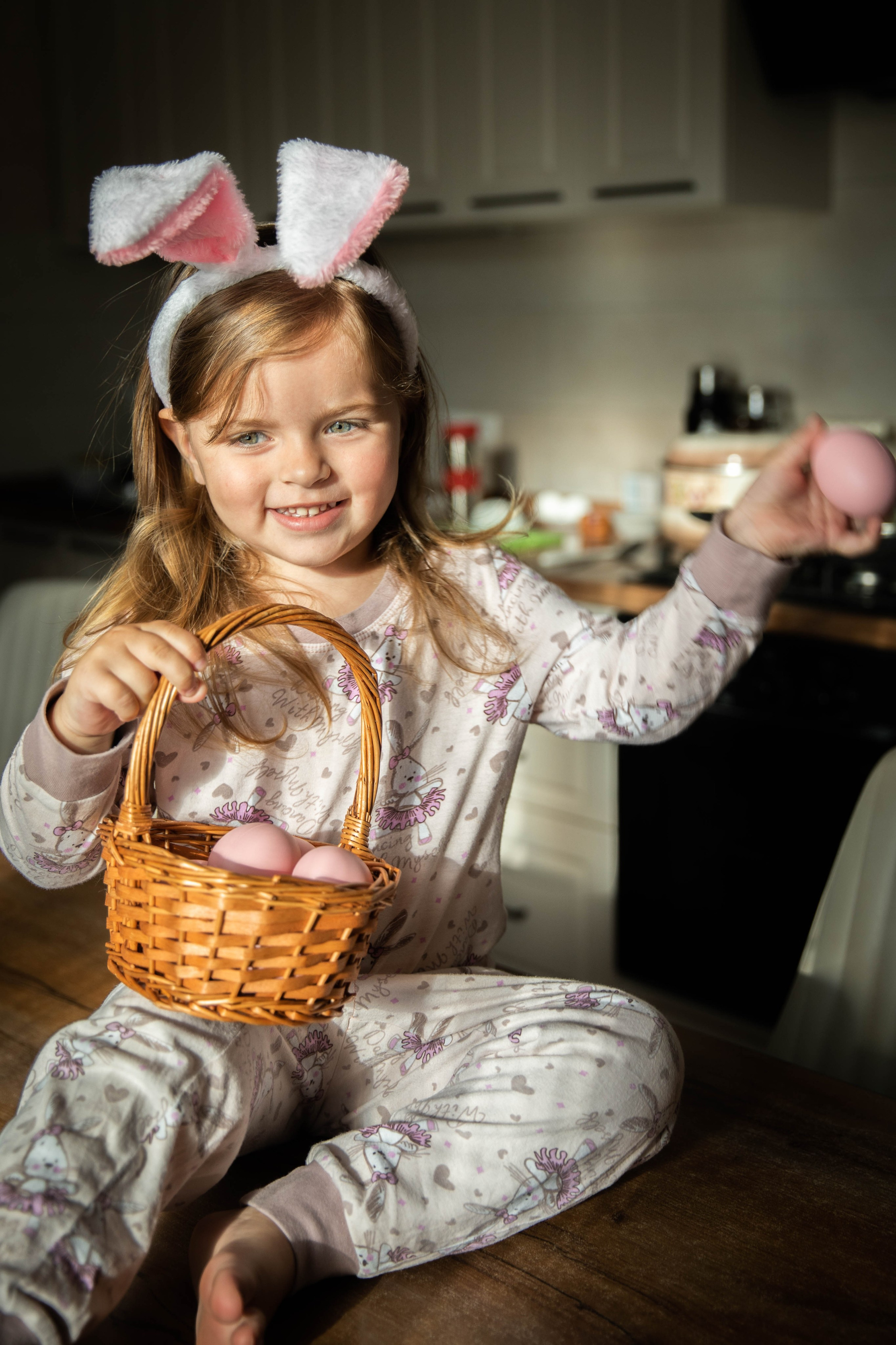 A little girl playing with pink eggs.