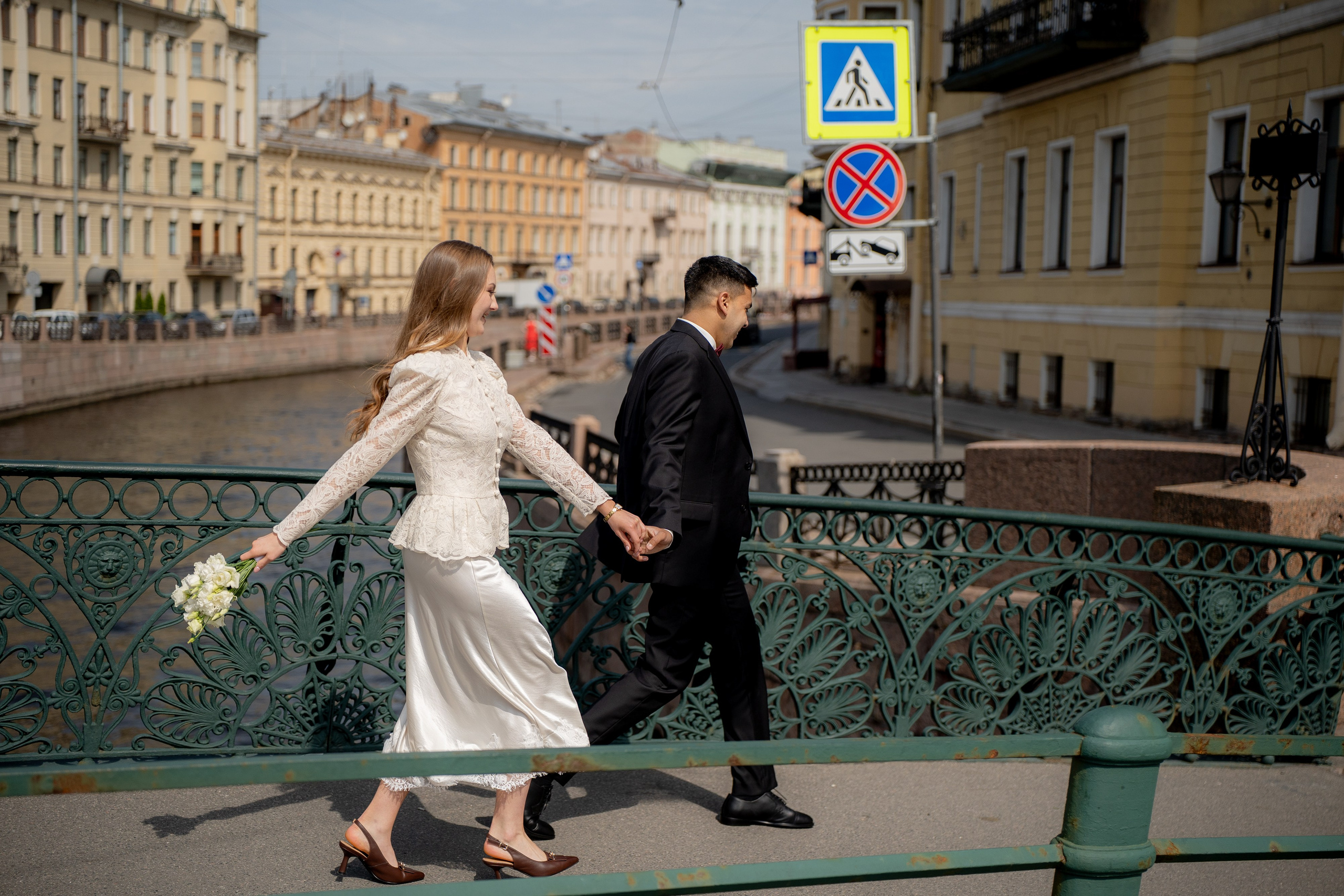 Свадебная фотосессия рядом с Атлантами и Зимней канавкой. Самые популярные места для свадебной фотосессии в Санкт-Петербурге. Пара идет по певческому мосту