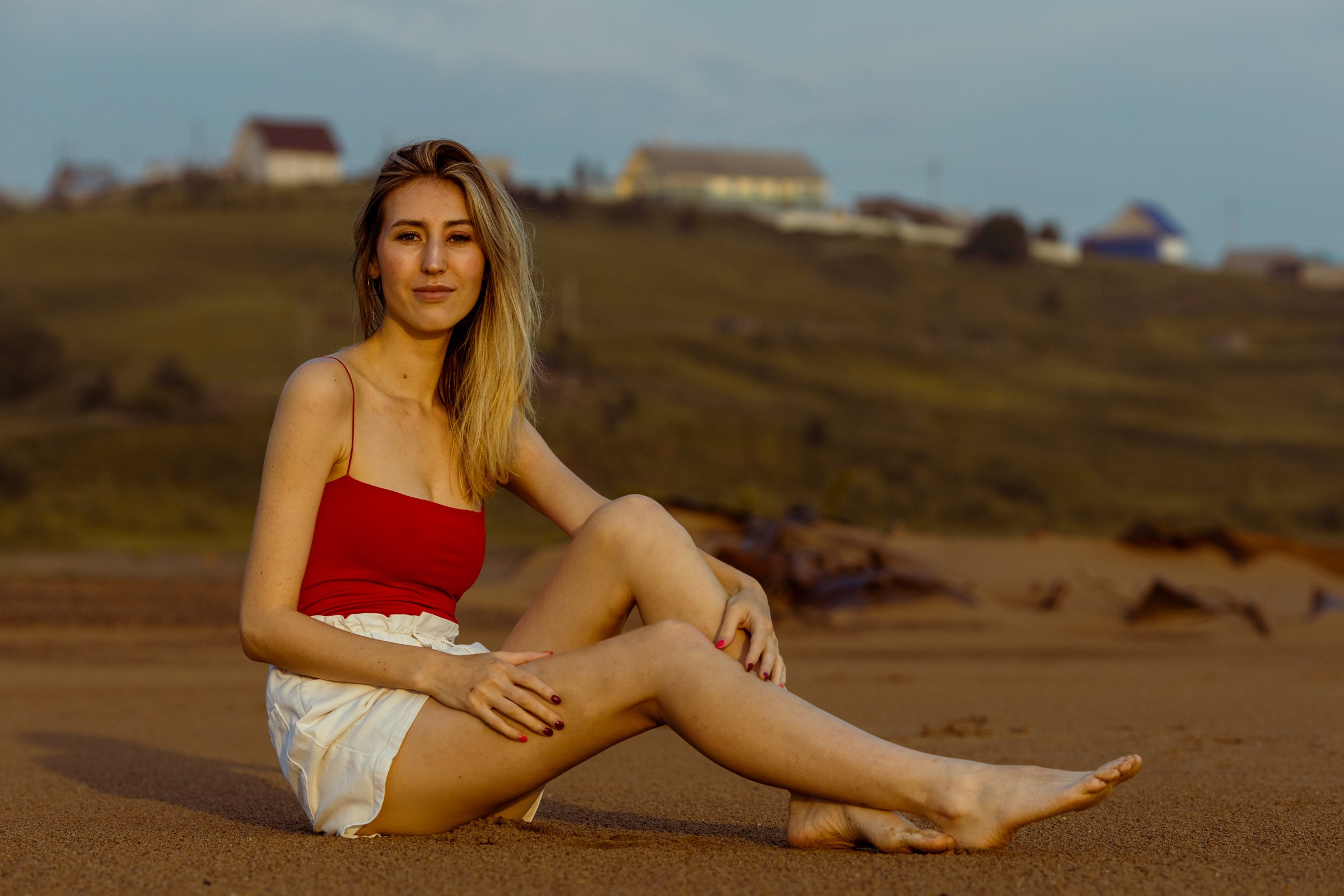 Девушка в красной майке сидит на пляже