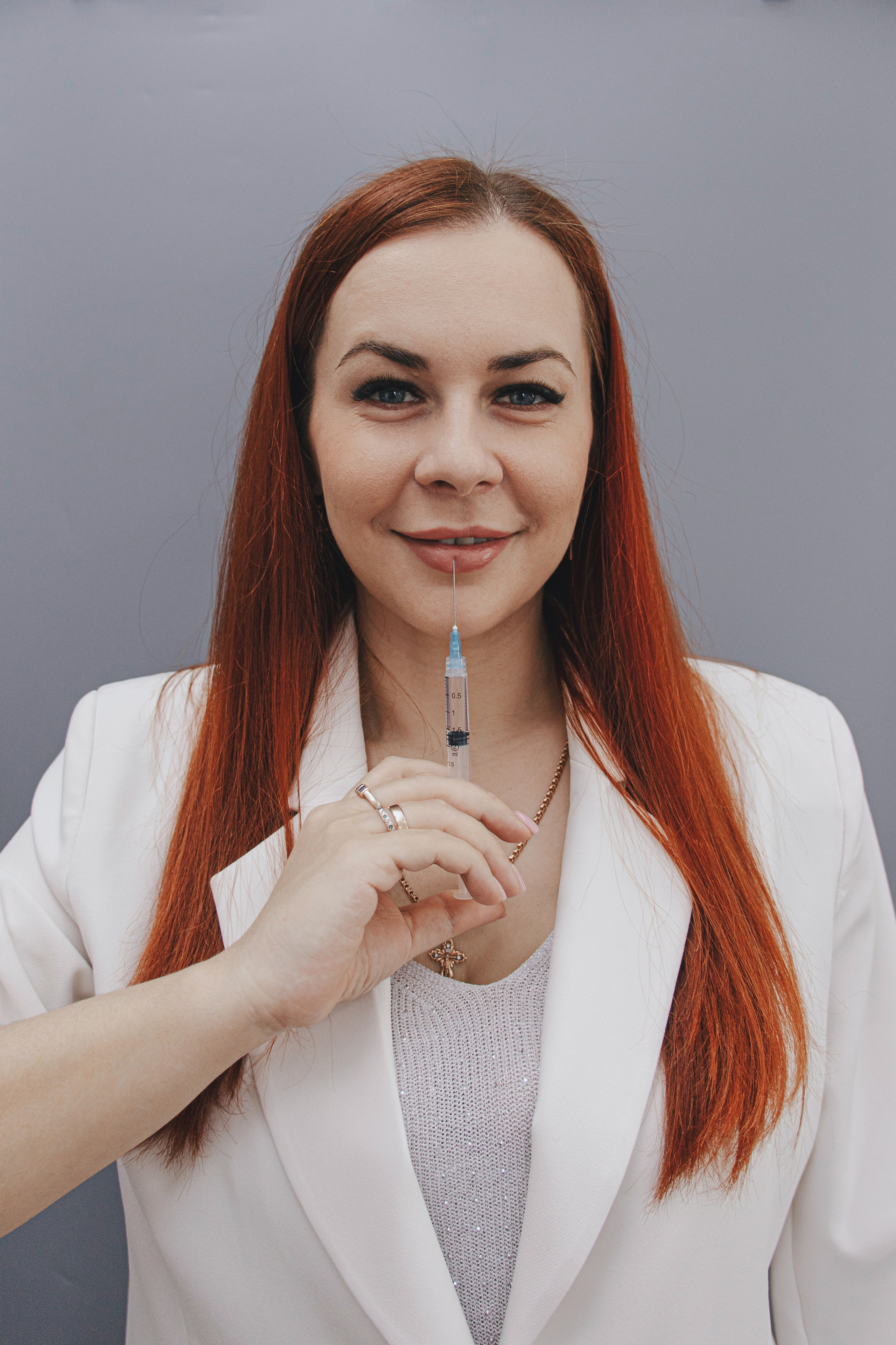 Косметолог с канюлями и шприцами в руках, готовящийся к процедуре инъекций в кабинете