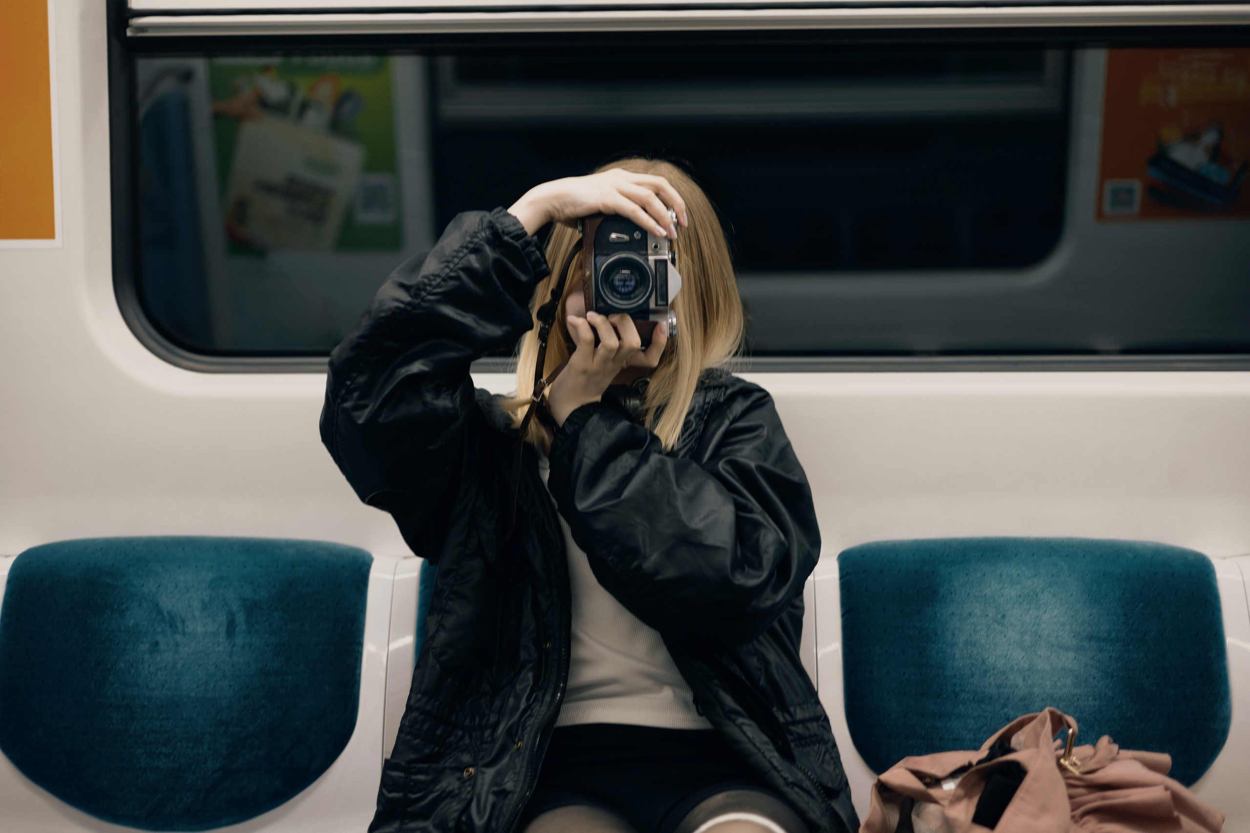 Девушка в кожаной куртке фотографирует в вагоне метро, урбан-съёмка
