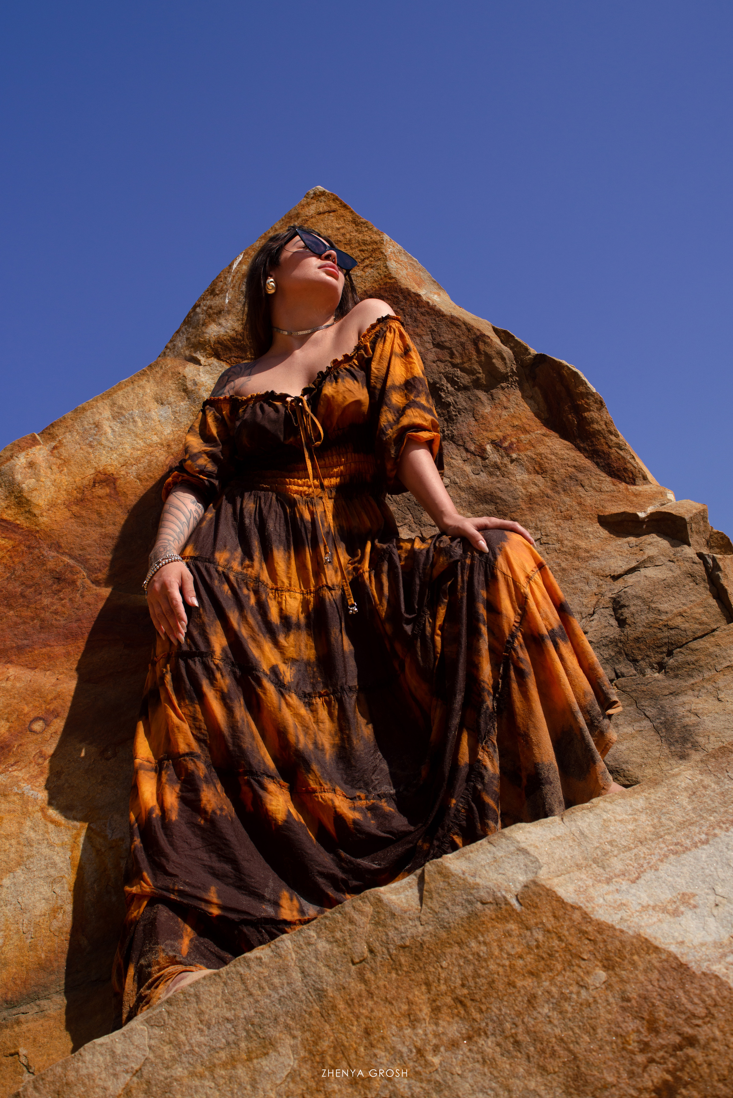 девушка в платье среди валунов и рыжих камней летом 