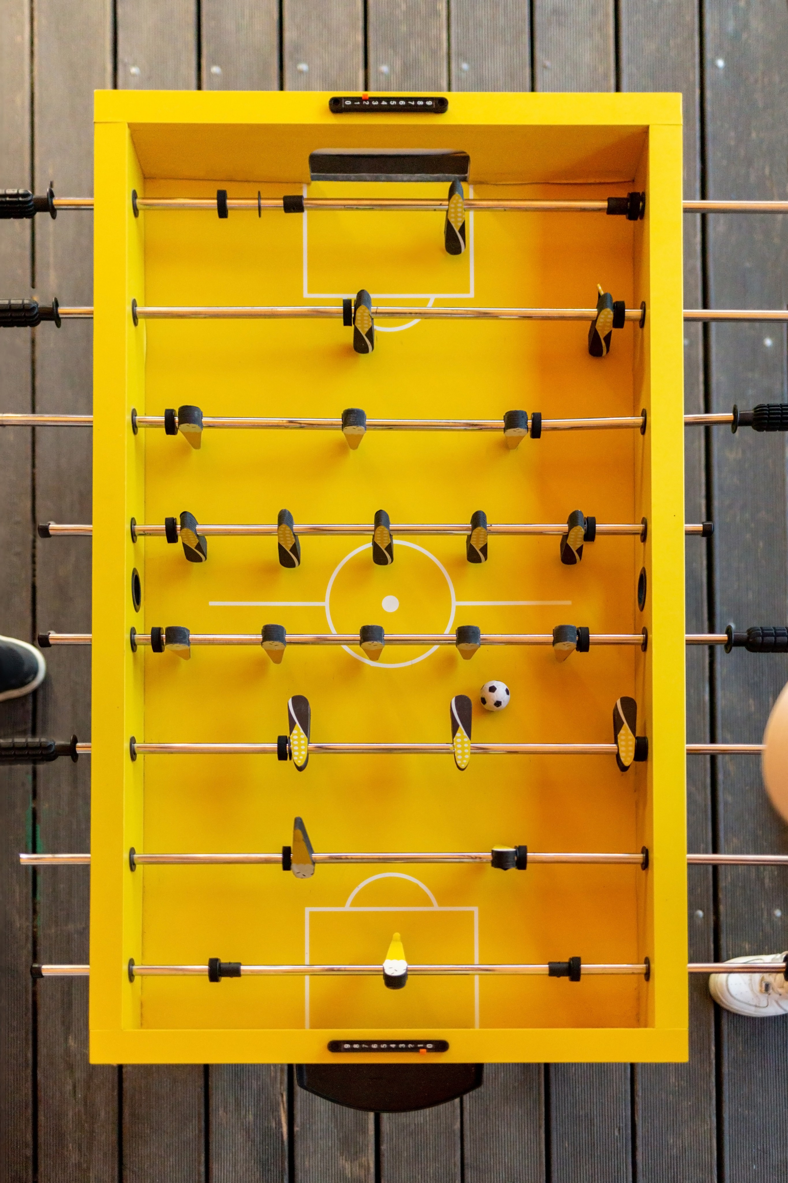 Настольный футбол ракурс сверху. Желтый кикер сверху. Люди играют в настольный футбол.