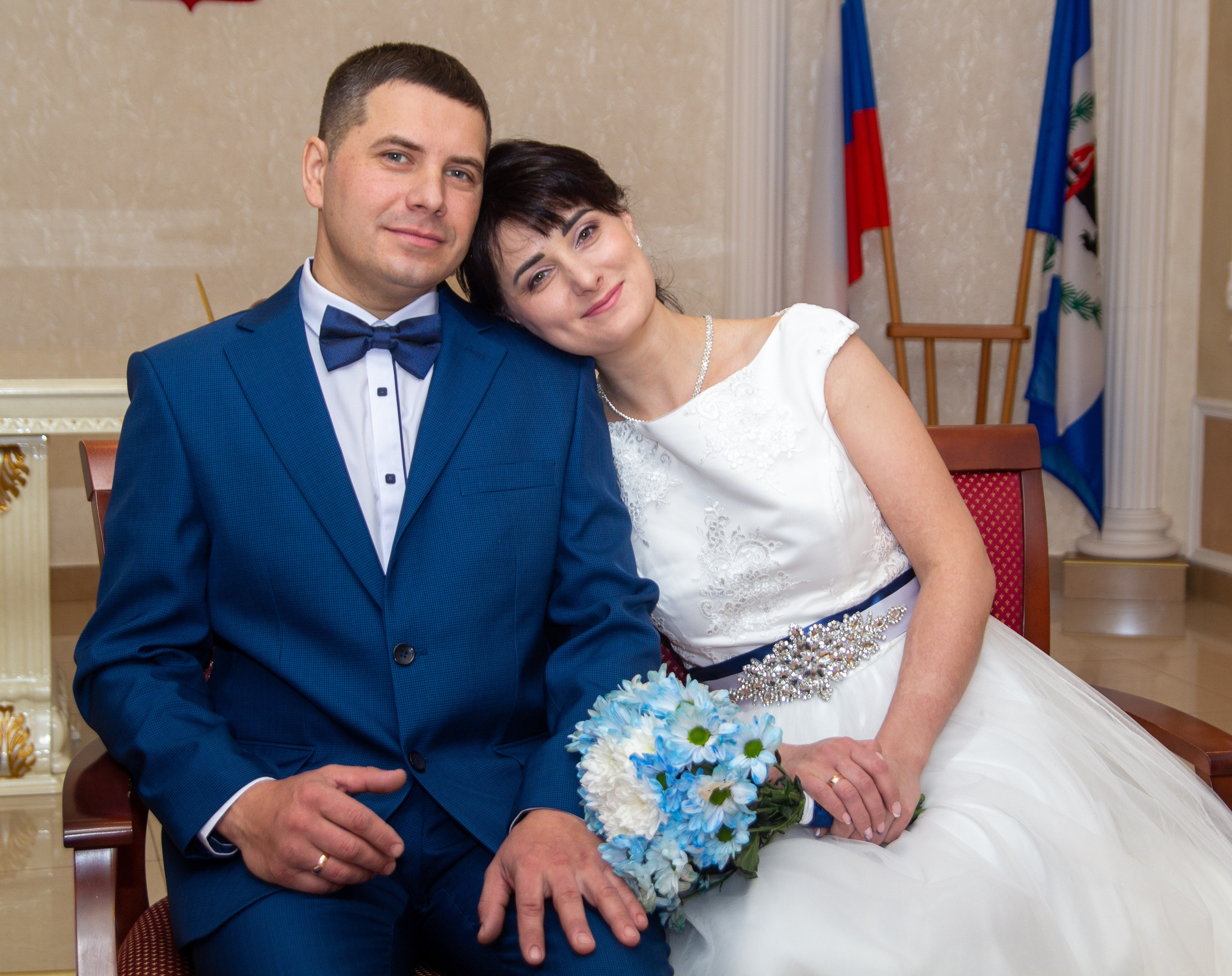 Жених и невеста сидят вместе, нежно прижавшись — момент уюта после регистрации.