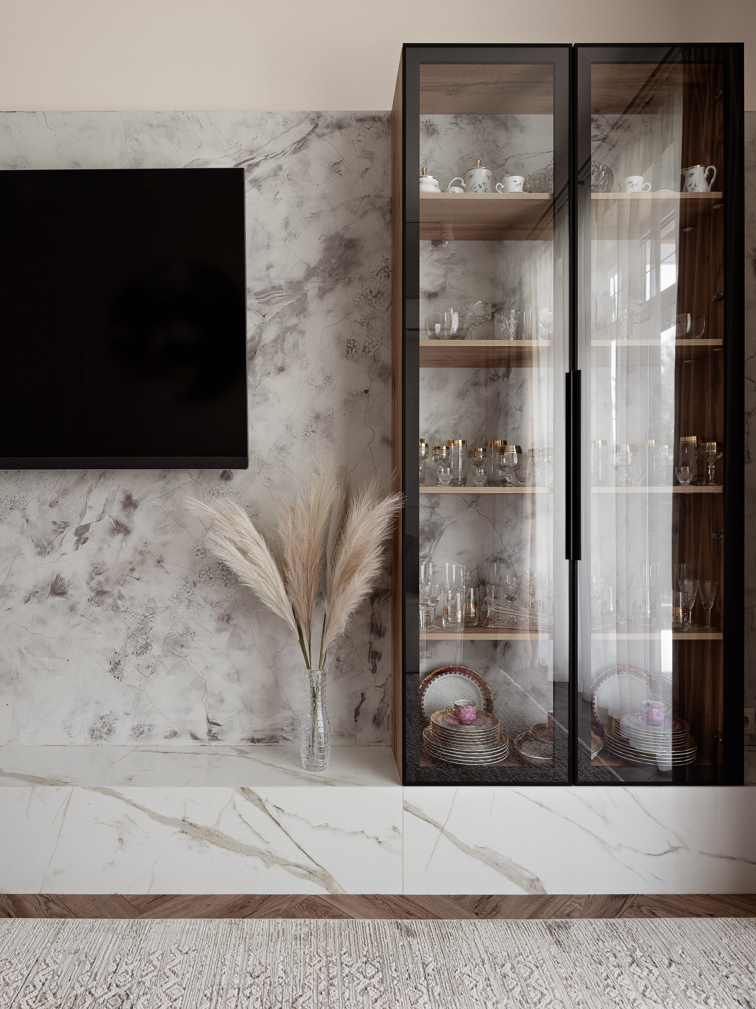 Стеклянный шкаф-витрина с сервизом и бокалами, установленный на фоне мраморной стены, декор с сухоцветами в вазе. Интерьер от дизайнера Алины Чередниченко, фото Сергея Денисенко.