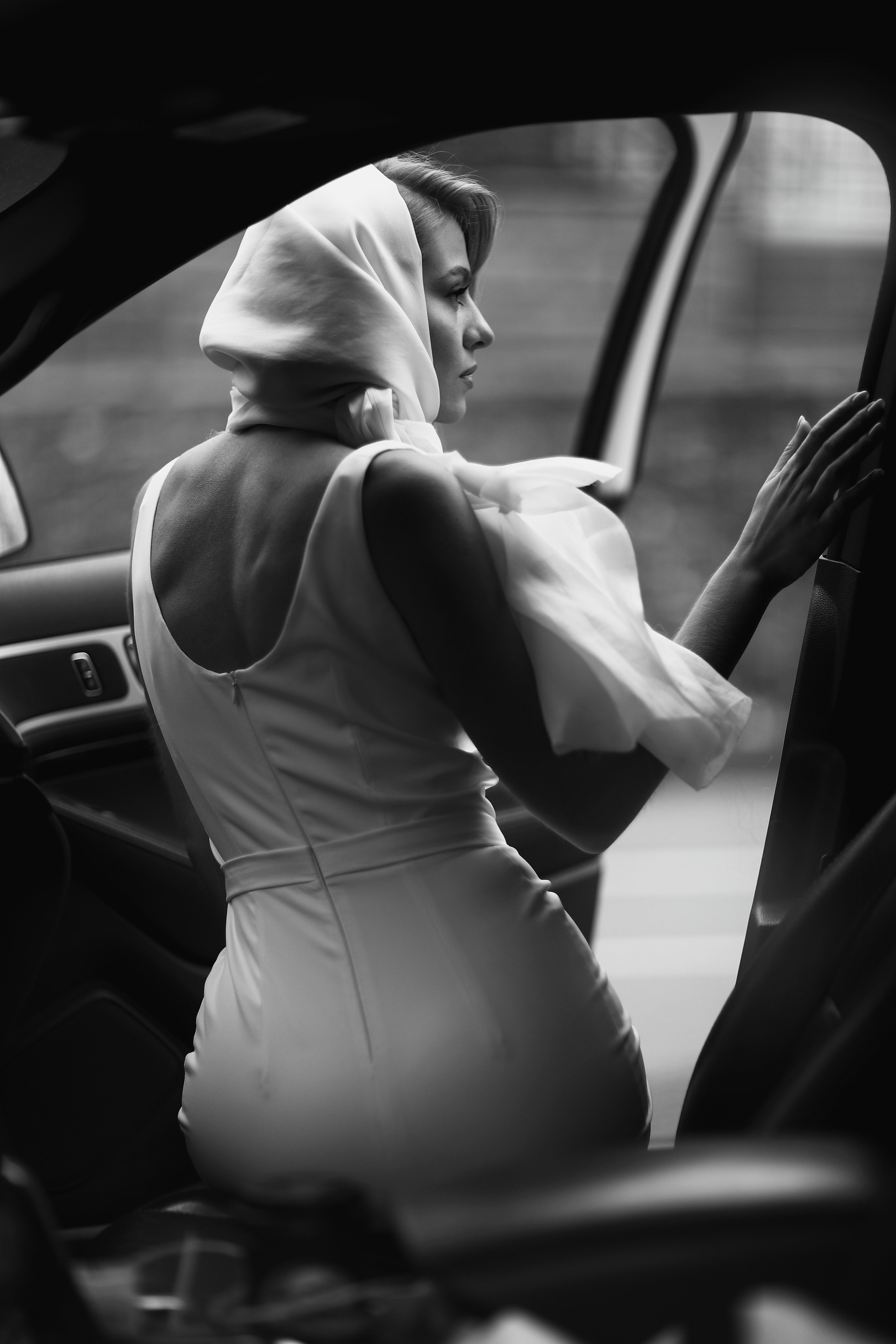 Черно-белый портрет девушки сидящей в автомобиле.