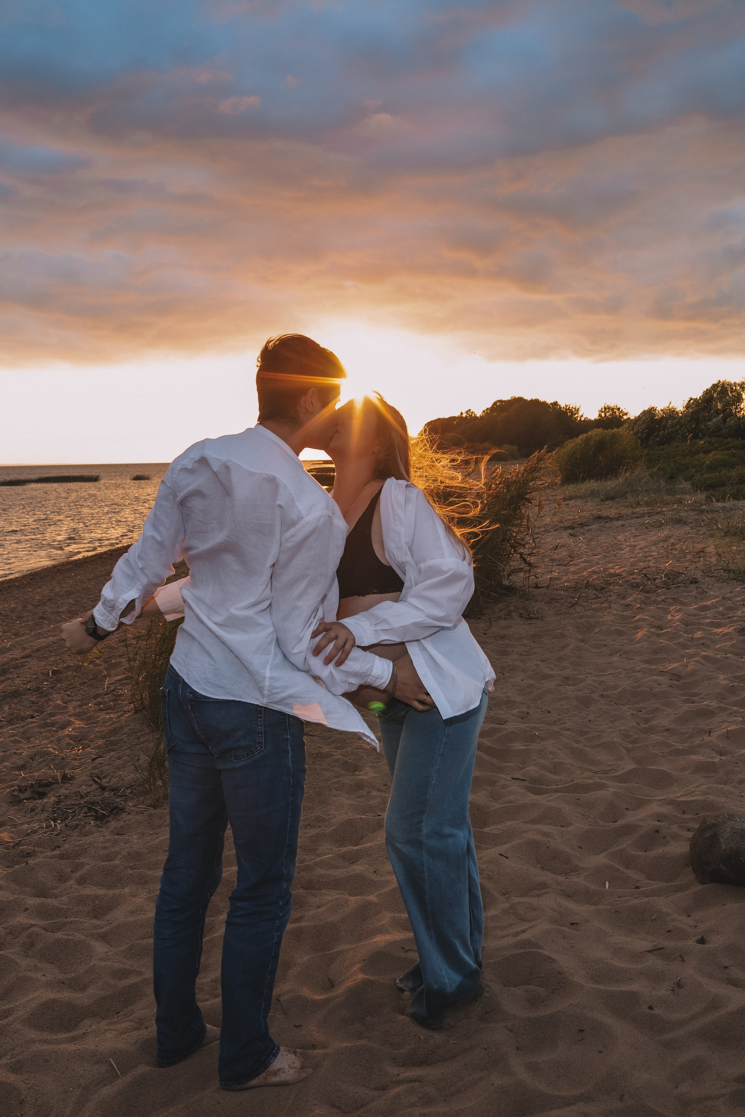 Мужчина обнимает девушку за живот, тёплый свет