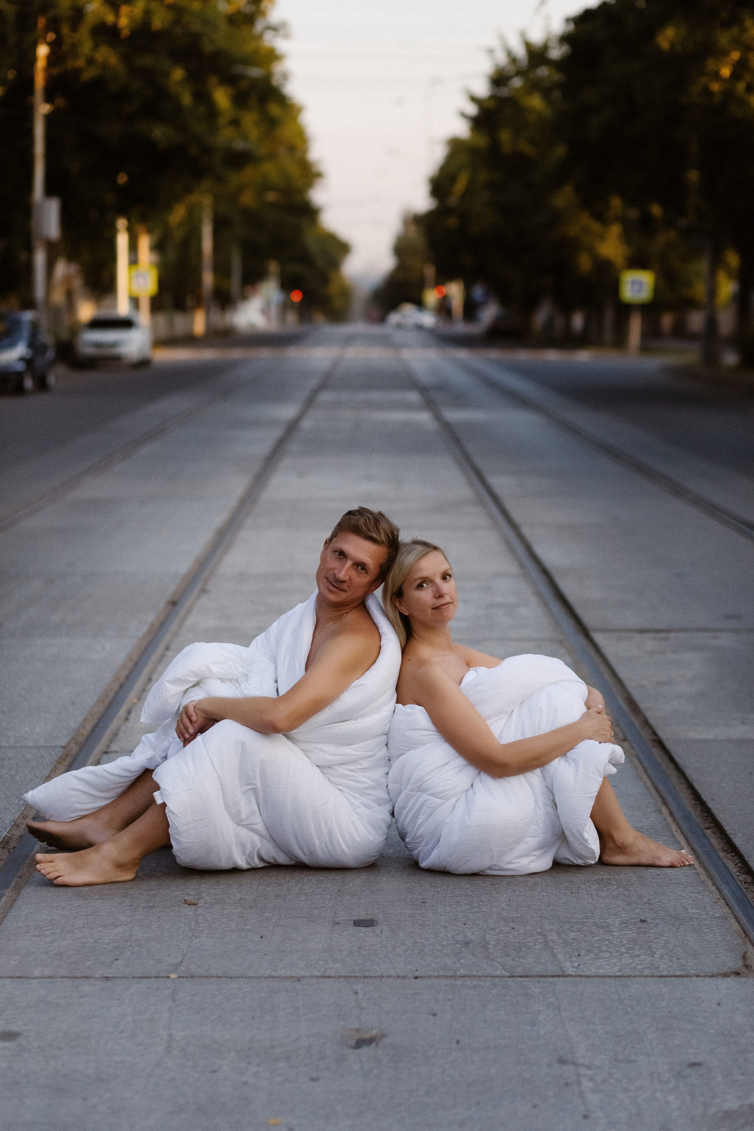 Олег и Мария в одеялах сидят на трамвайных рельсах на улице Фрунзе в Таганроге, уютная фотосессия