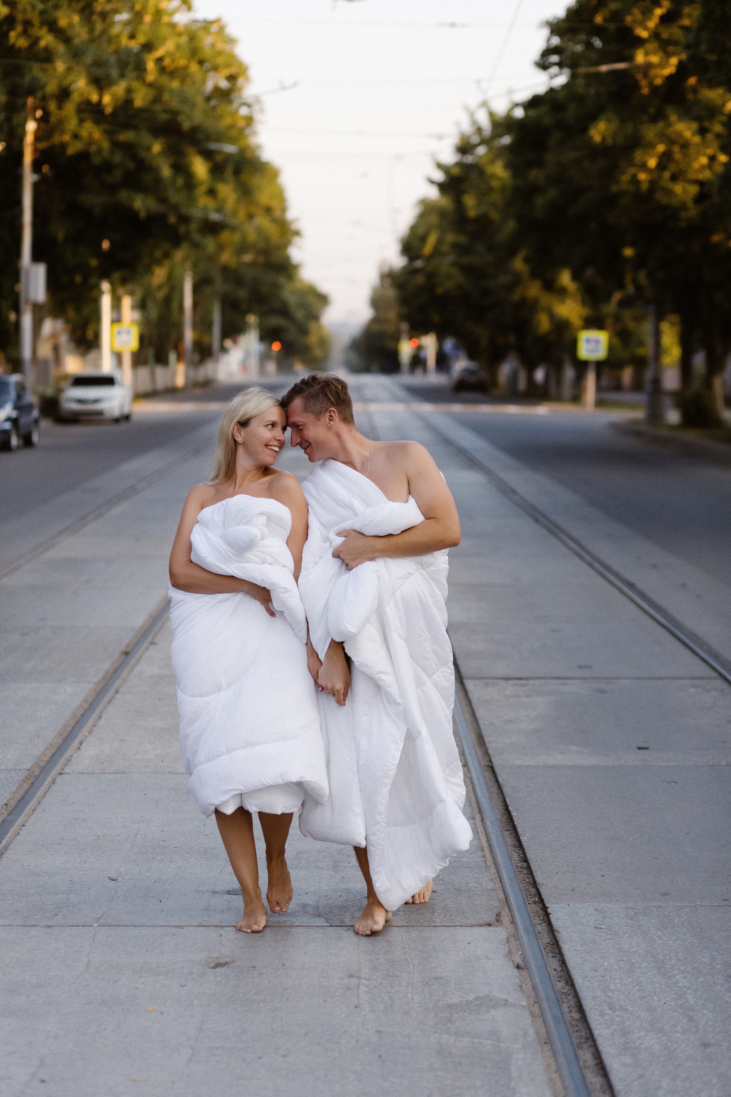 Романтическая пара в белых одеялах на улице Фрунзе в Таганроге, утренний свет и трамвайные рельсы