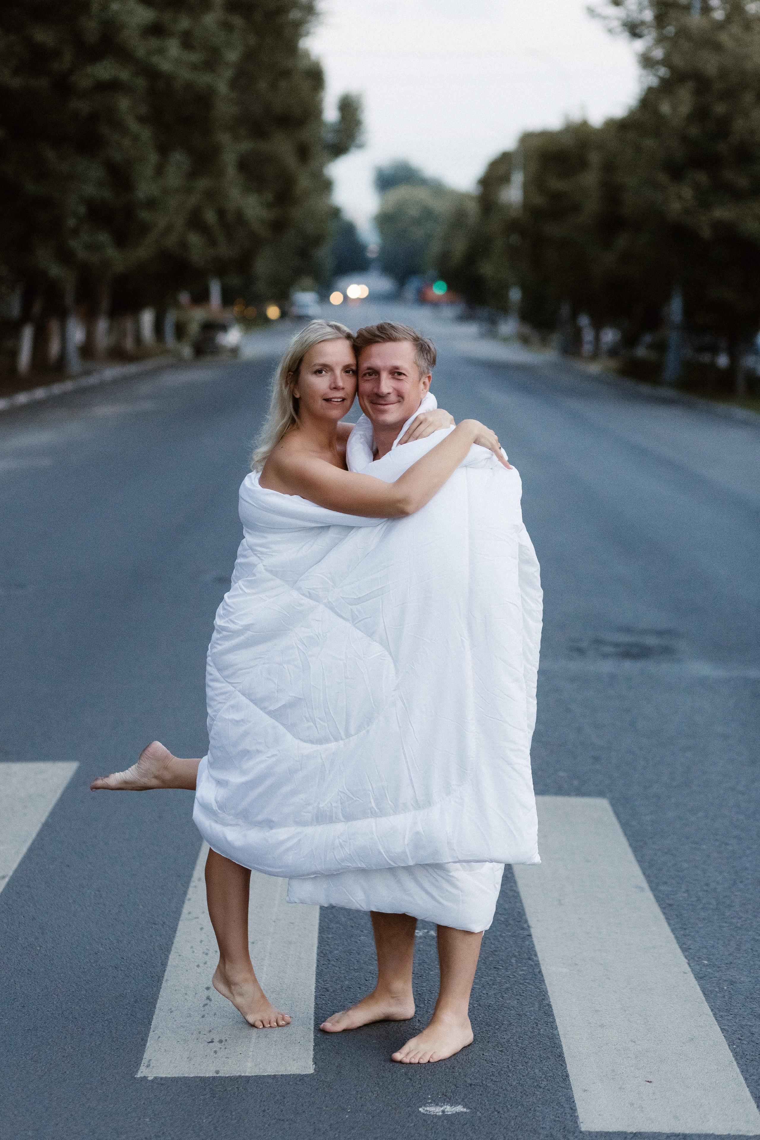 Счастливая пара в одеялах на пустынной улице Петровская возле Театра Чехова в Таганроге