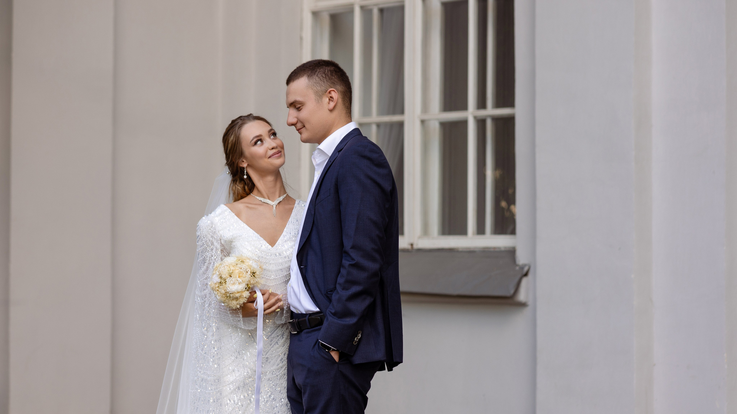 Невеста любуется женихом у окна.