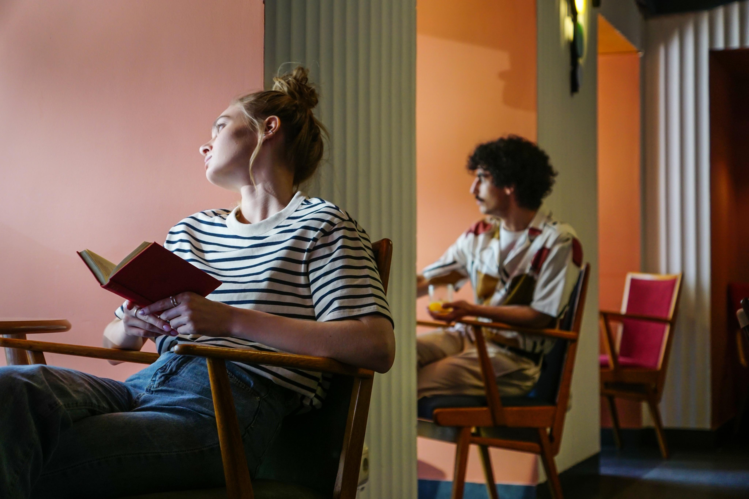 Мужчина и девушка с книгой сидят друг за другом