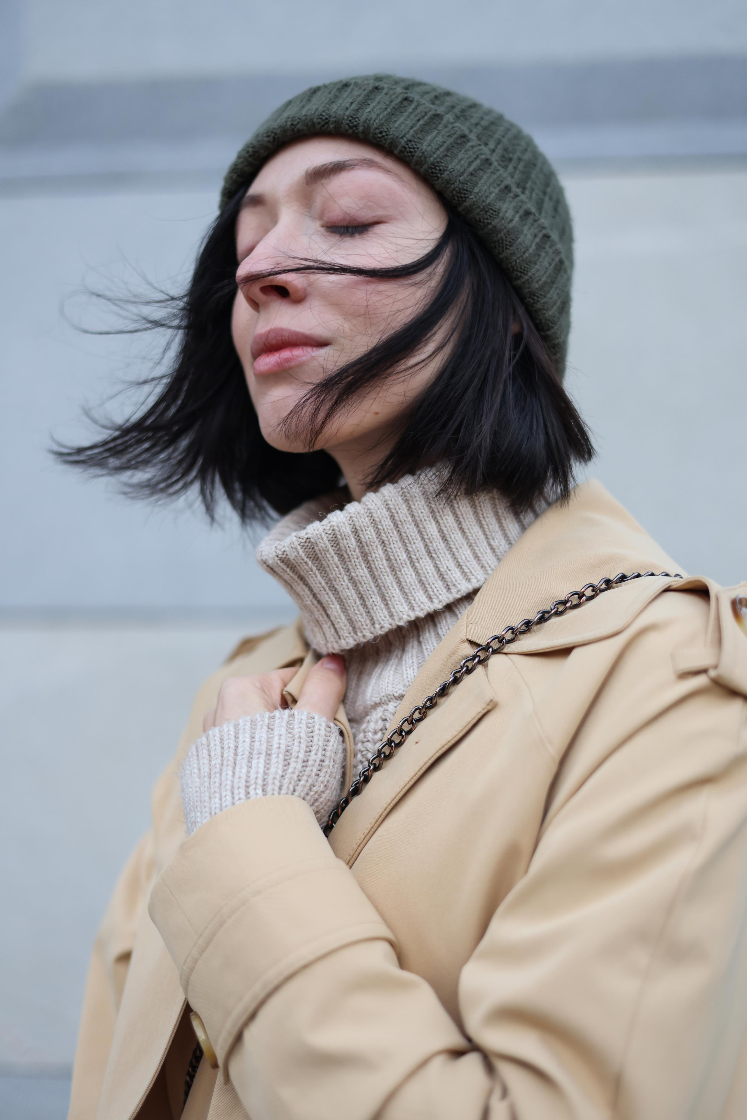 Девушка Наталья Штин на улице в шапке и пальто с развивающиеся волосами на ветру