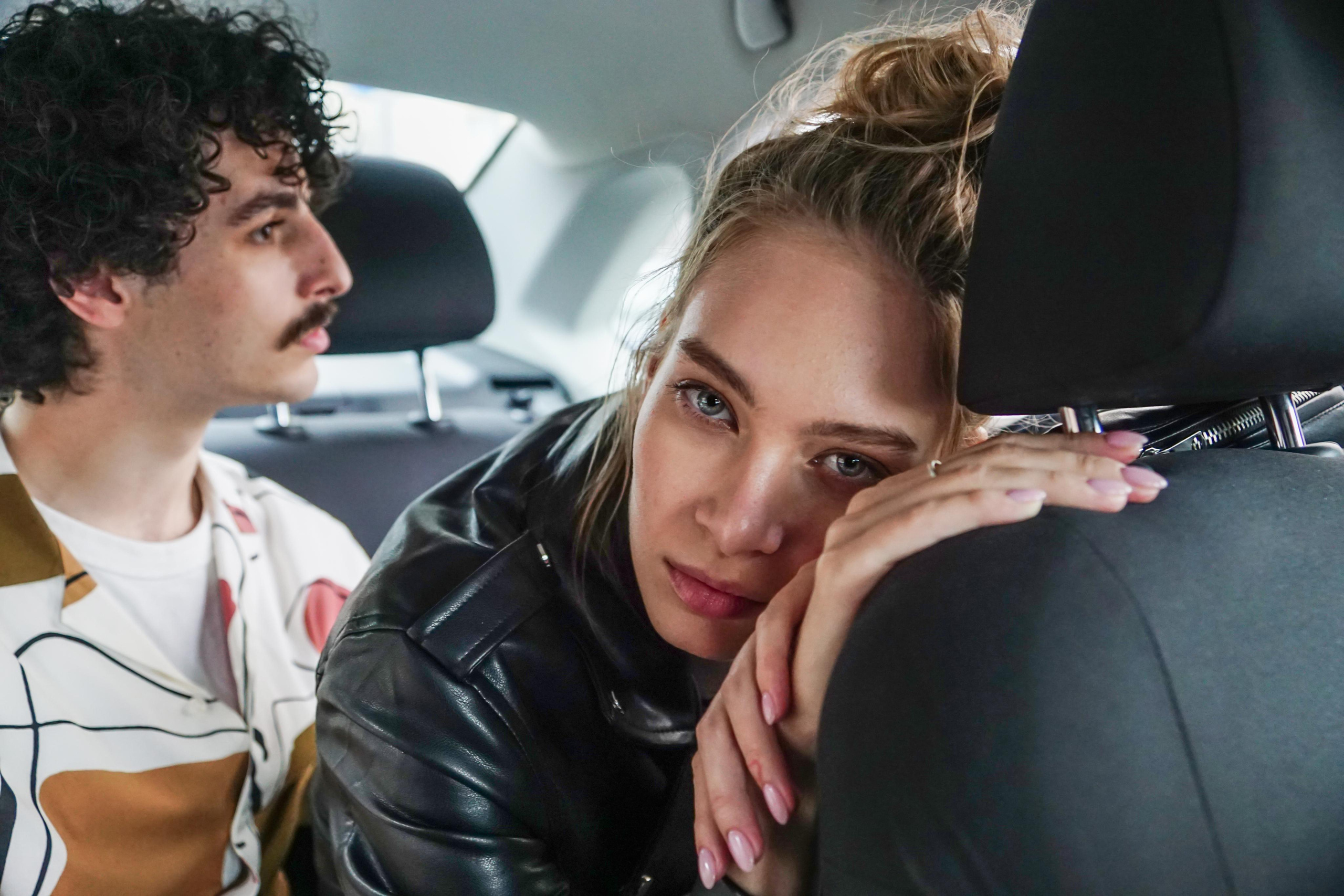 пара в машине на заднем сидении, девушка облокотилась на водительское сиденье