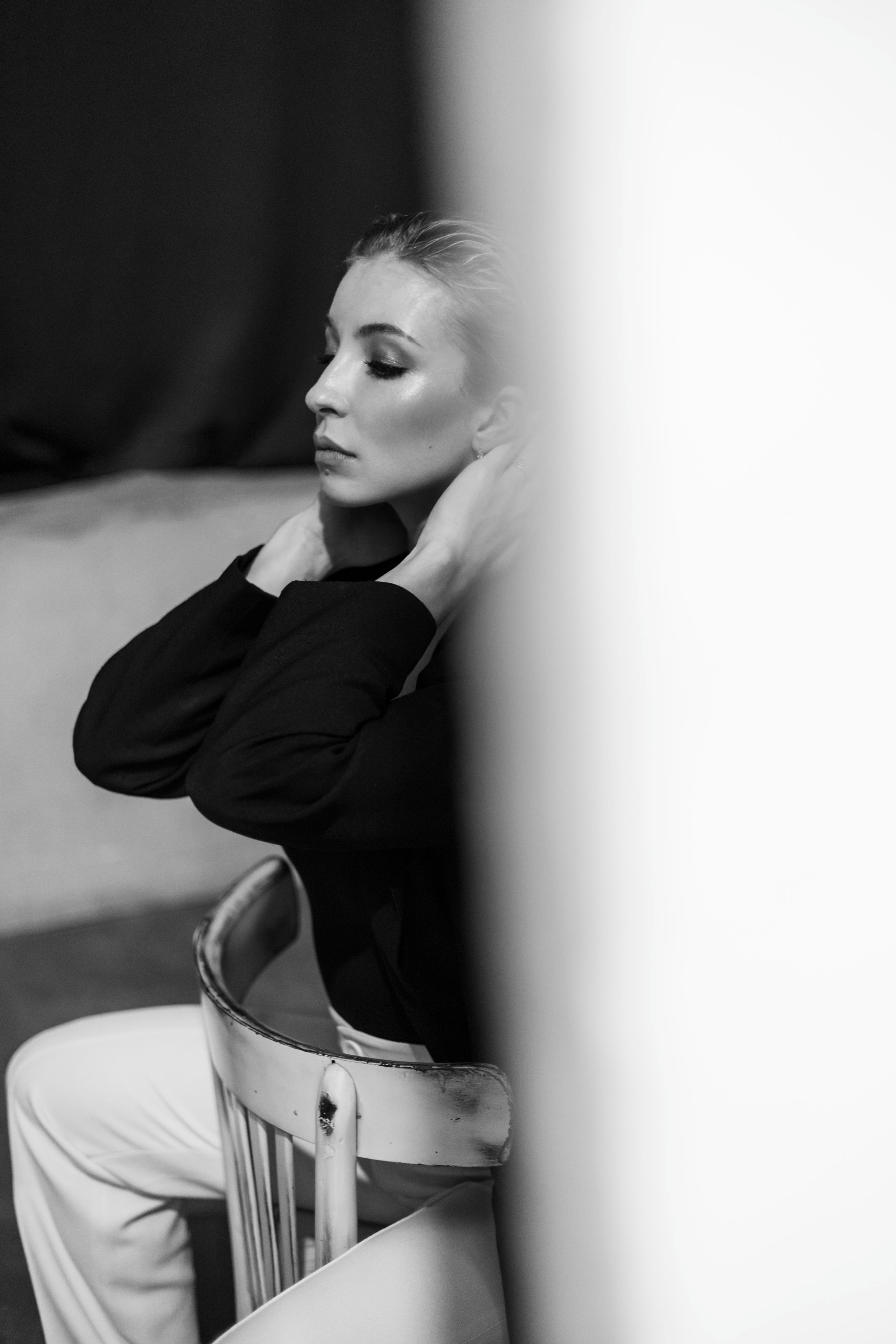 Девушка Софья Горбунова сидящая на стуле придерживает волосы с надменным взглядом. Фотосессия в студии.