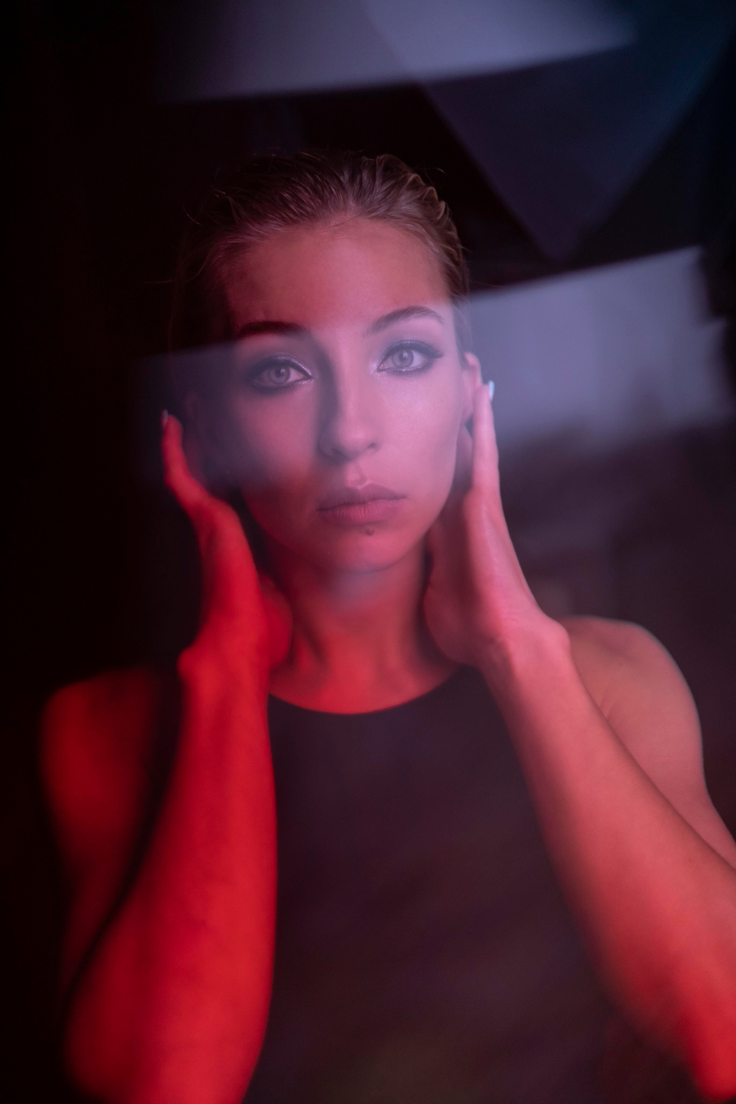 Девушка Софья Горбунова с бликами держится за шею смотря прямо в кадр. Фотосессия в студии