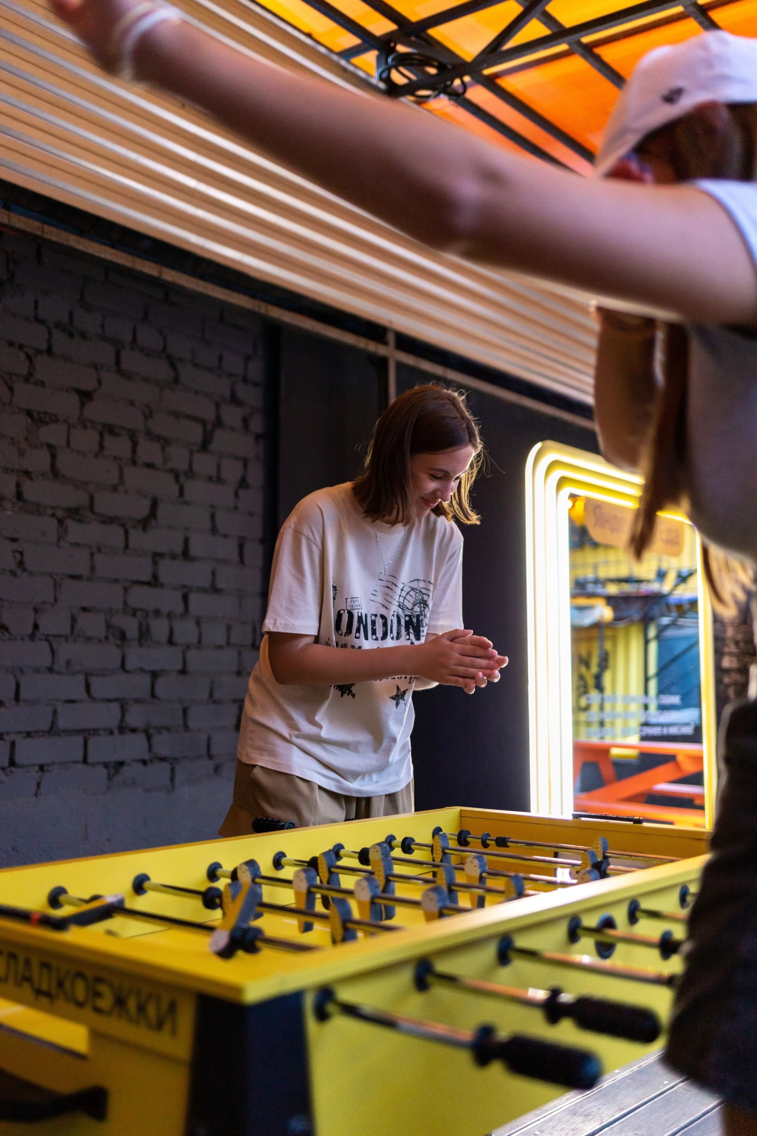 Девушка выиграла в настольный футбол. Девушка радуется и улыбается.