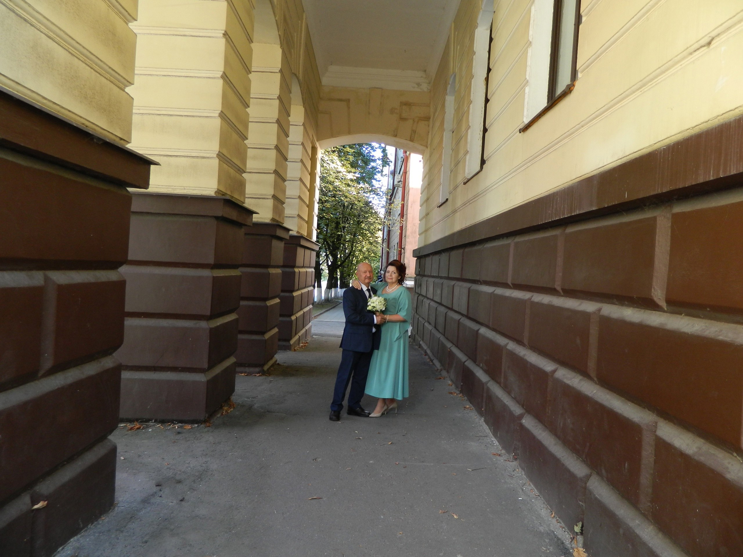 молодожёны идут под аркой