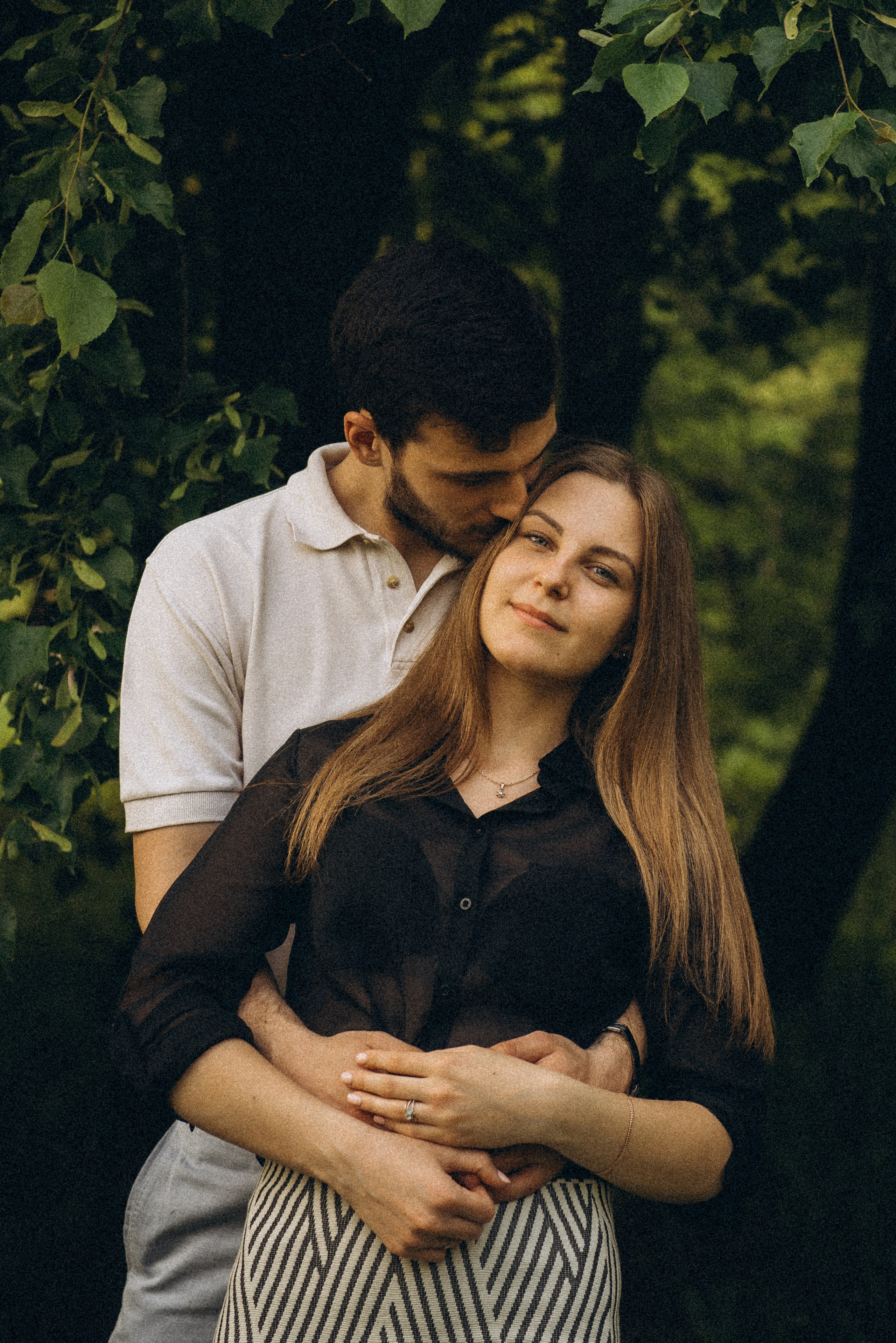 Романтический портрет: он целует её в щеку, она смотрит в кадр. Фотосессия в парке у Речного вокзала, Новосибирск, фотограф Василий Дан.