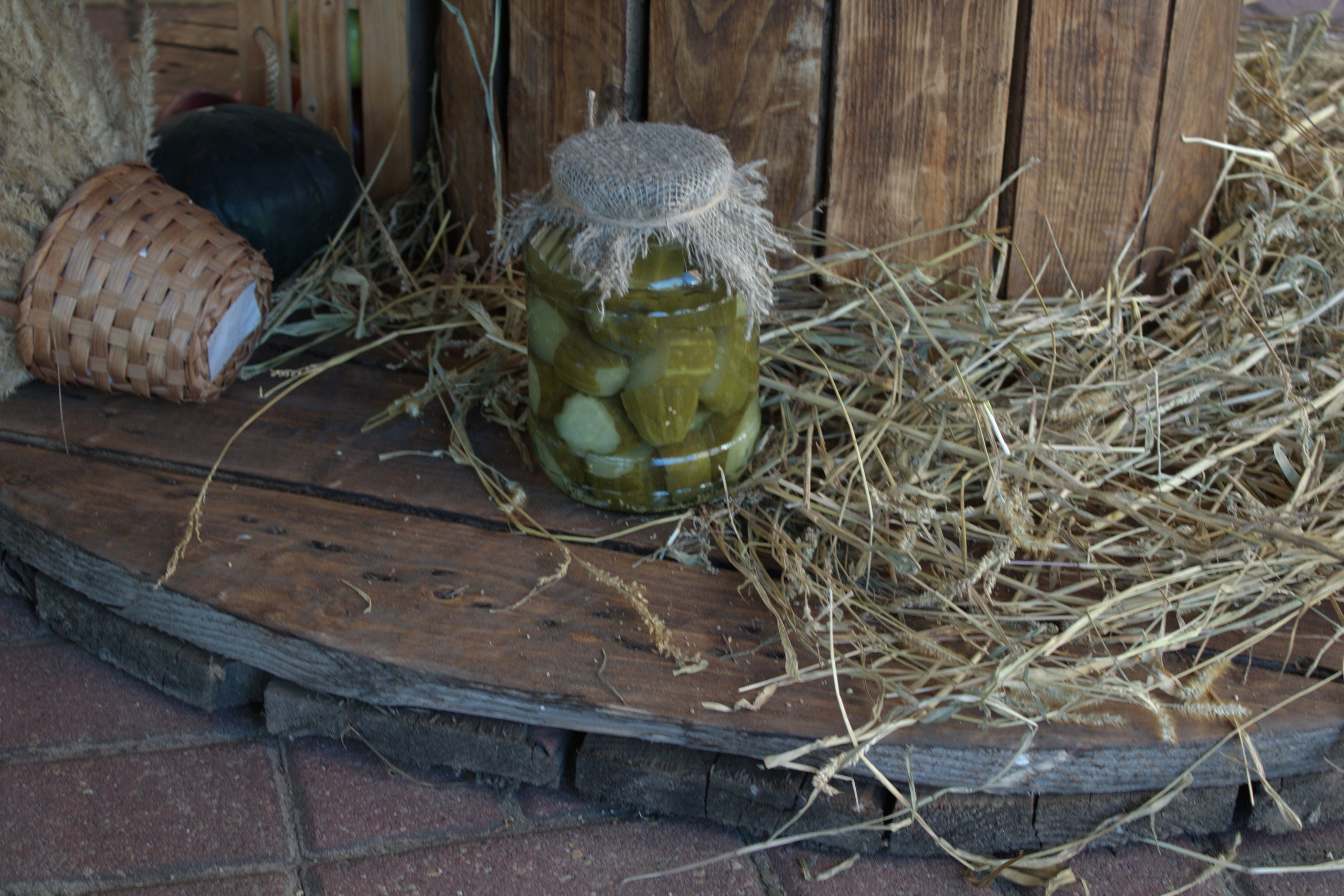 банка солёных огурцов на фоне сена