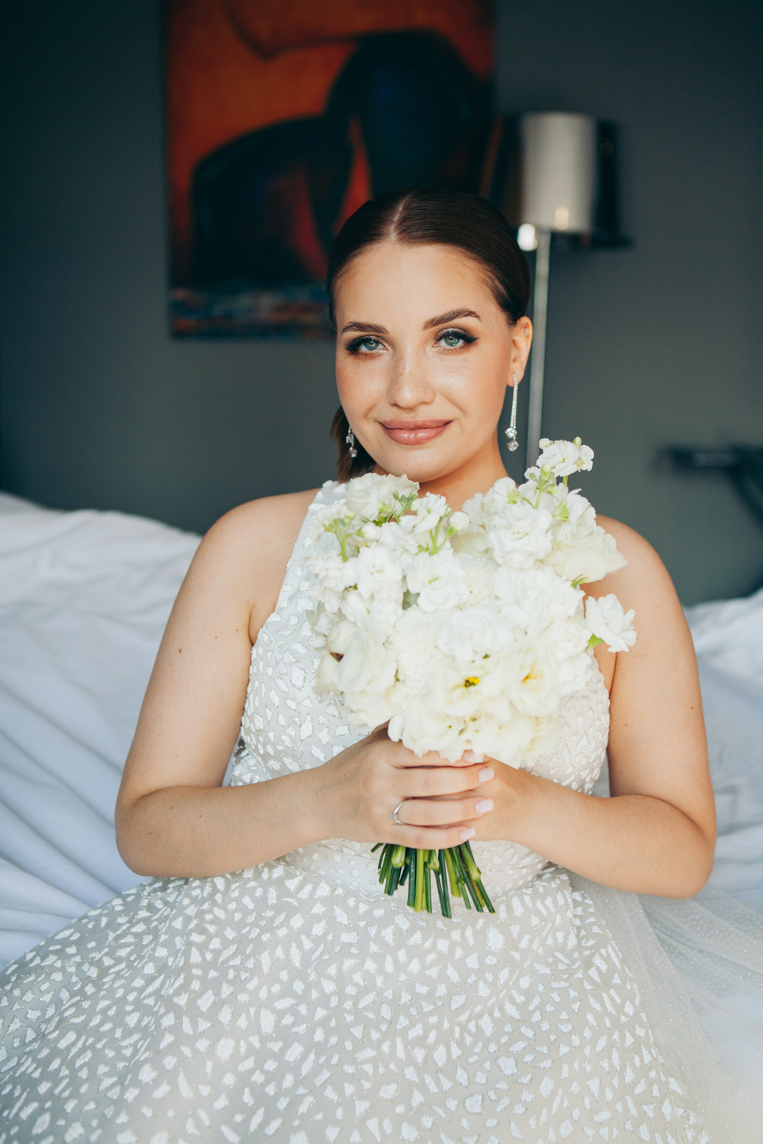 невеста сидит в номере в ожидании жениха с букетом цветов