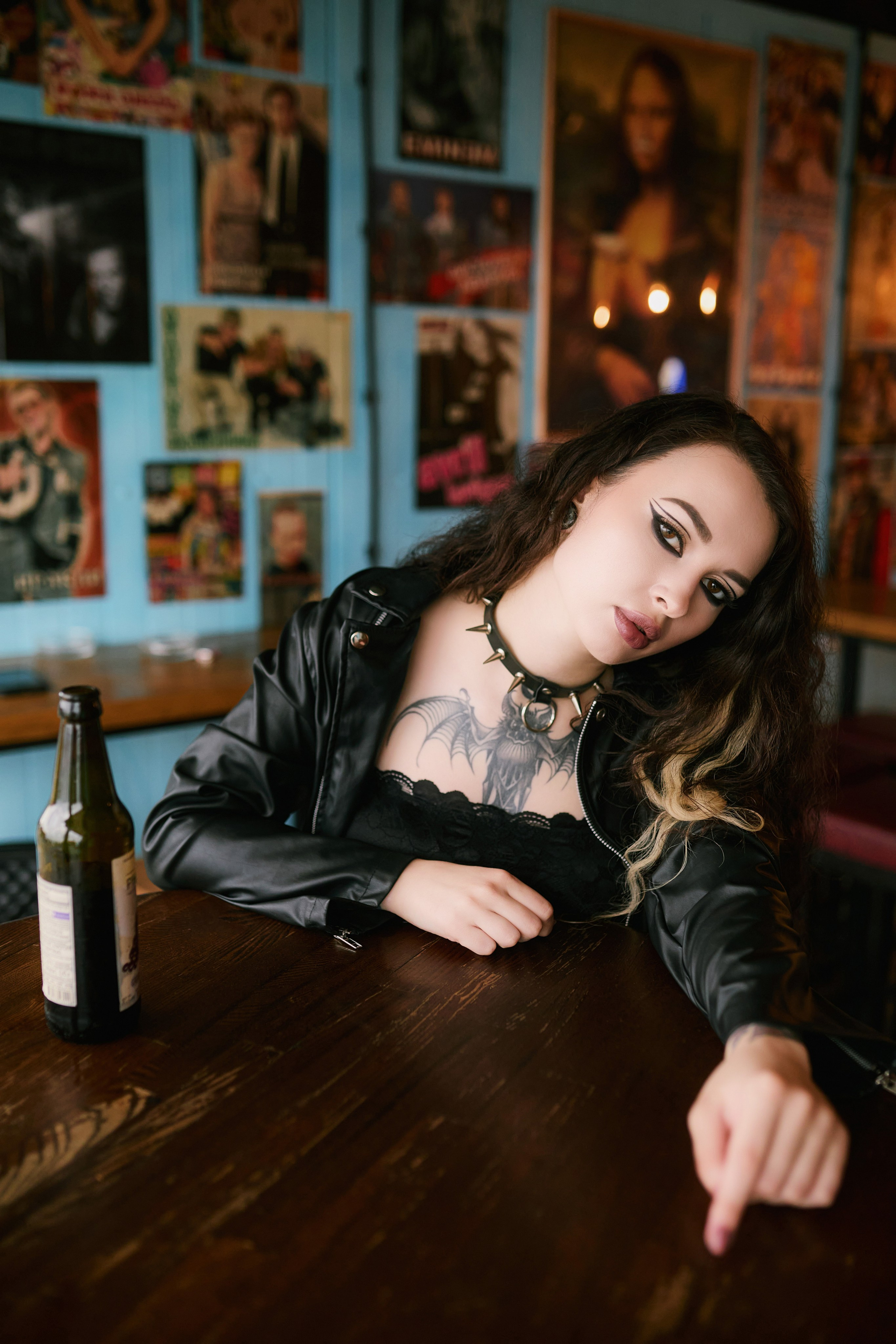 Татуированная девушка в чёрной одежде и кожаной куртке ложится на барный стол во Владивостоке